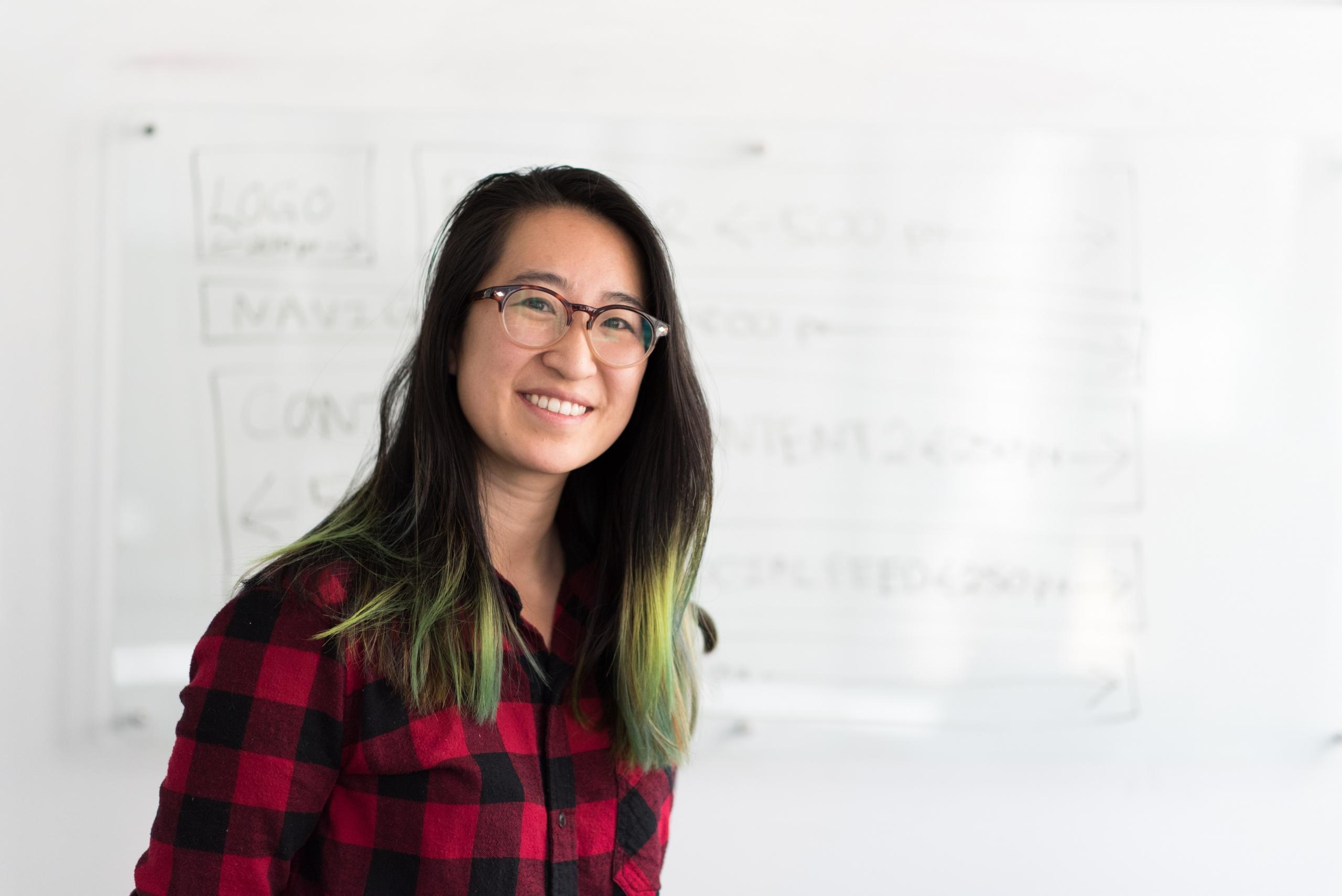 A korean teacher standing beside a whiteboard.