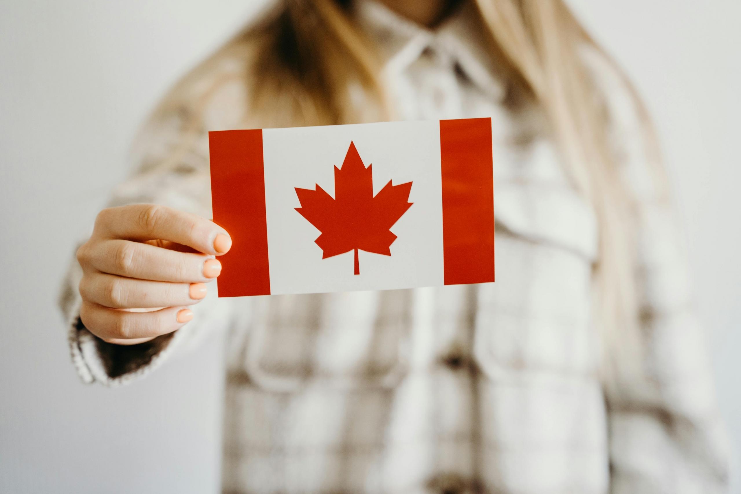 A woman holds a small Canada flag.