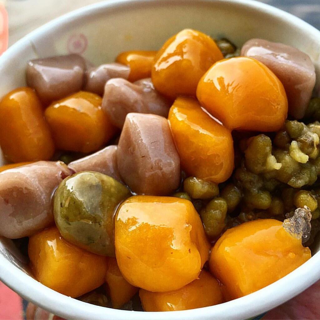 Balls of Taro (Yam Balls) served in a china bowl, the balls are orange, green and pale brown in colour.