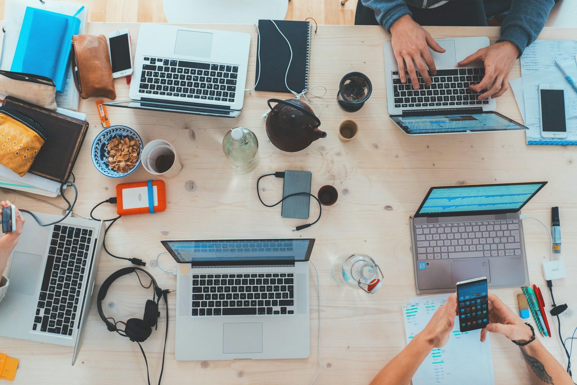 people working at a desk with laptop computers