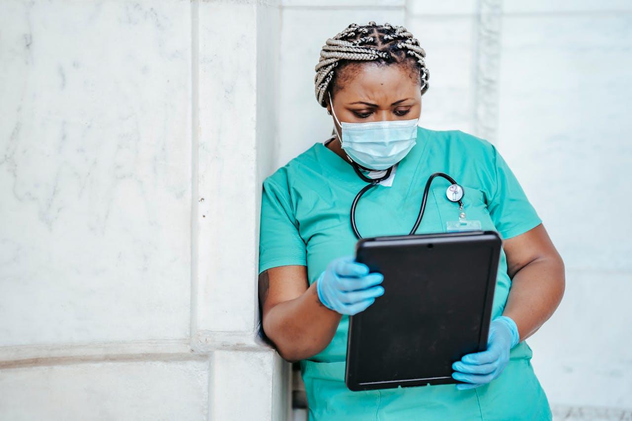 A nurse checking a report while leaning against a wall. 