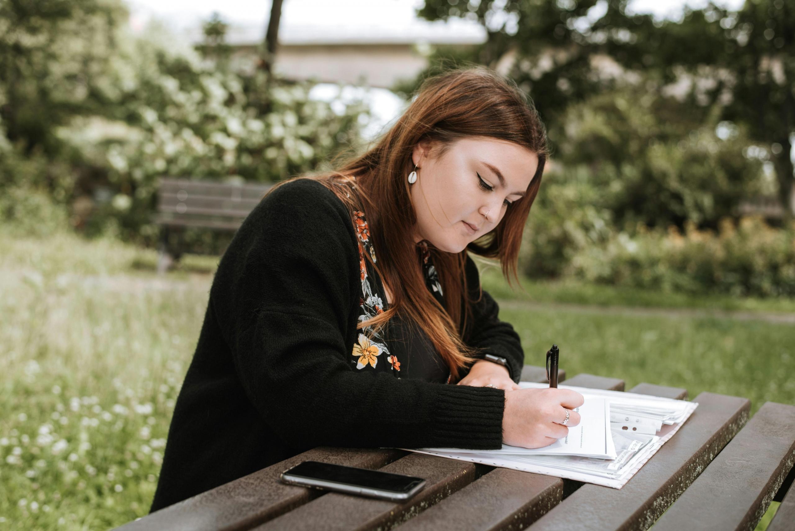 a female student works on an essay outdoors.