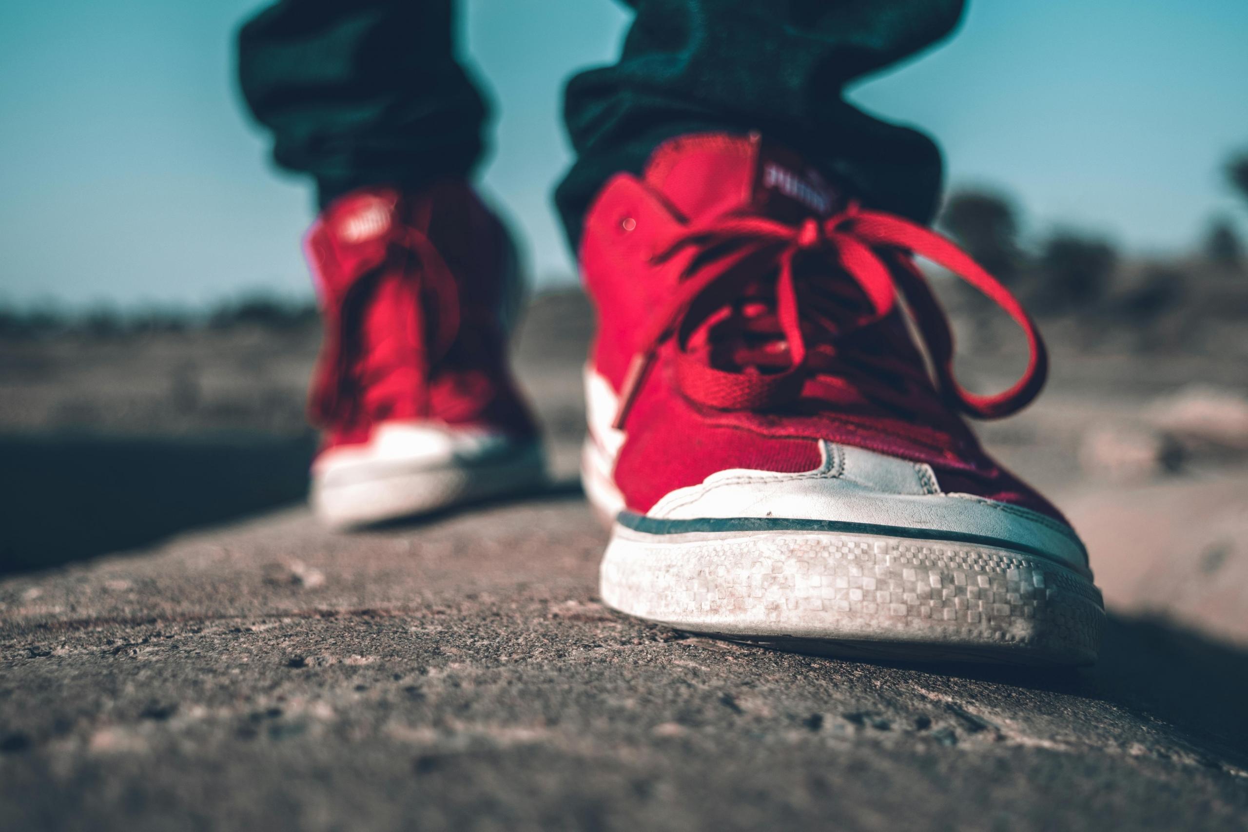 a person with red shoes walks on pavement.