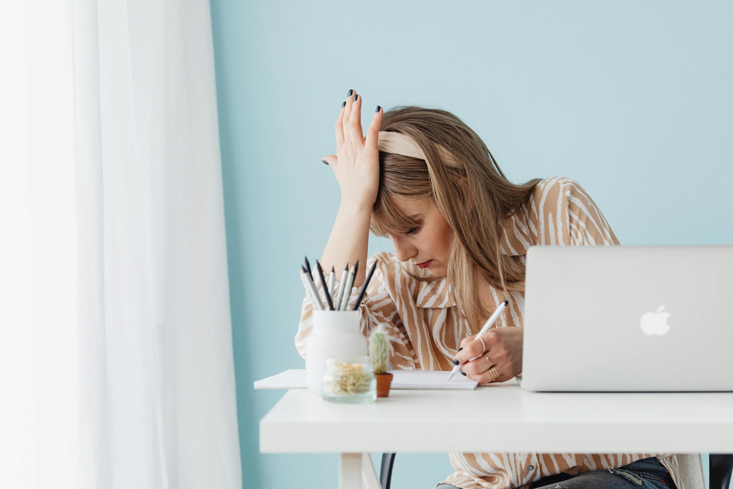 a woman appears stressed as she works in front of a computer.