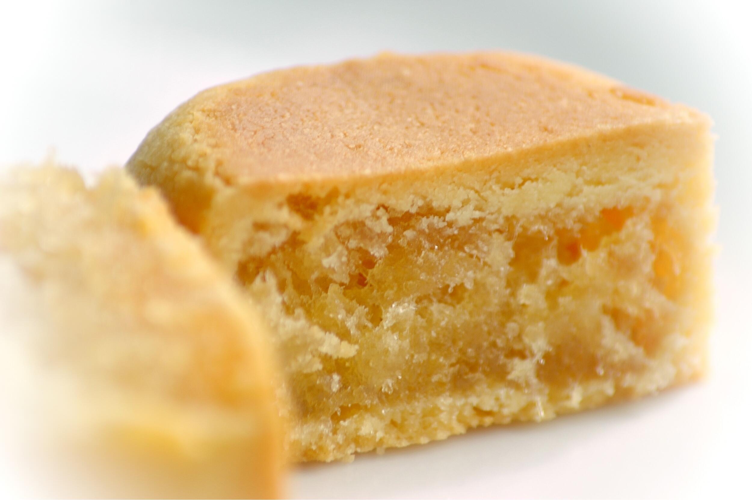 A slice of soft, golden cake revealing a moist interior with hints of fruit bits, resting on a white plate.