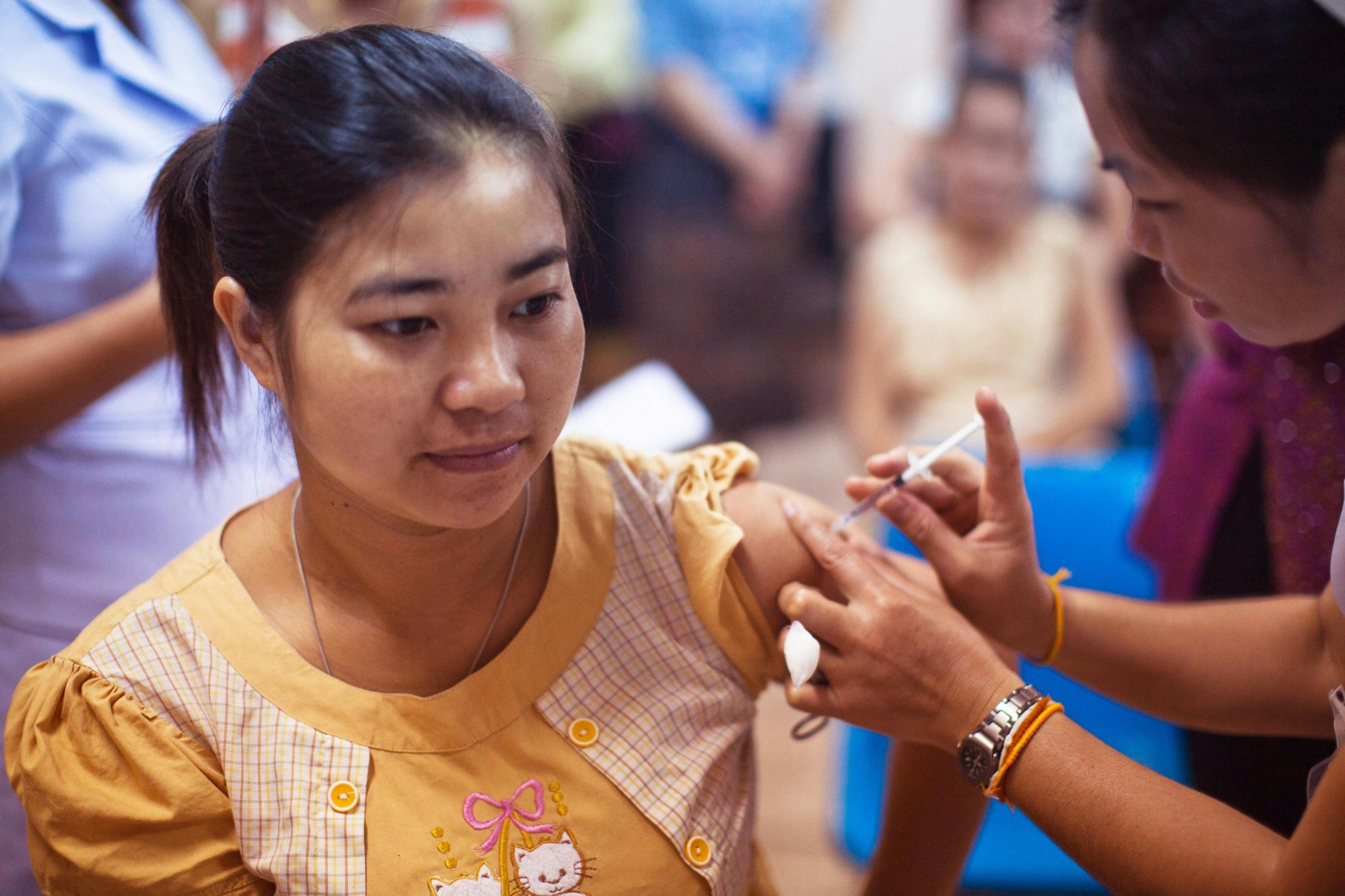A woman gives another woman a vaccine.