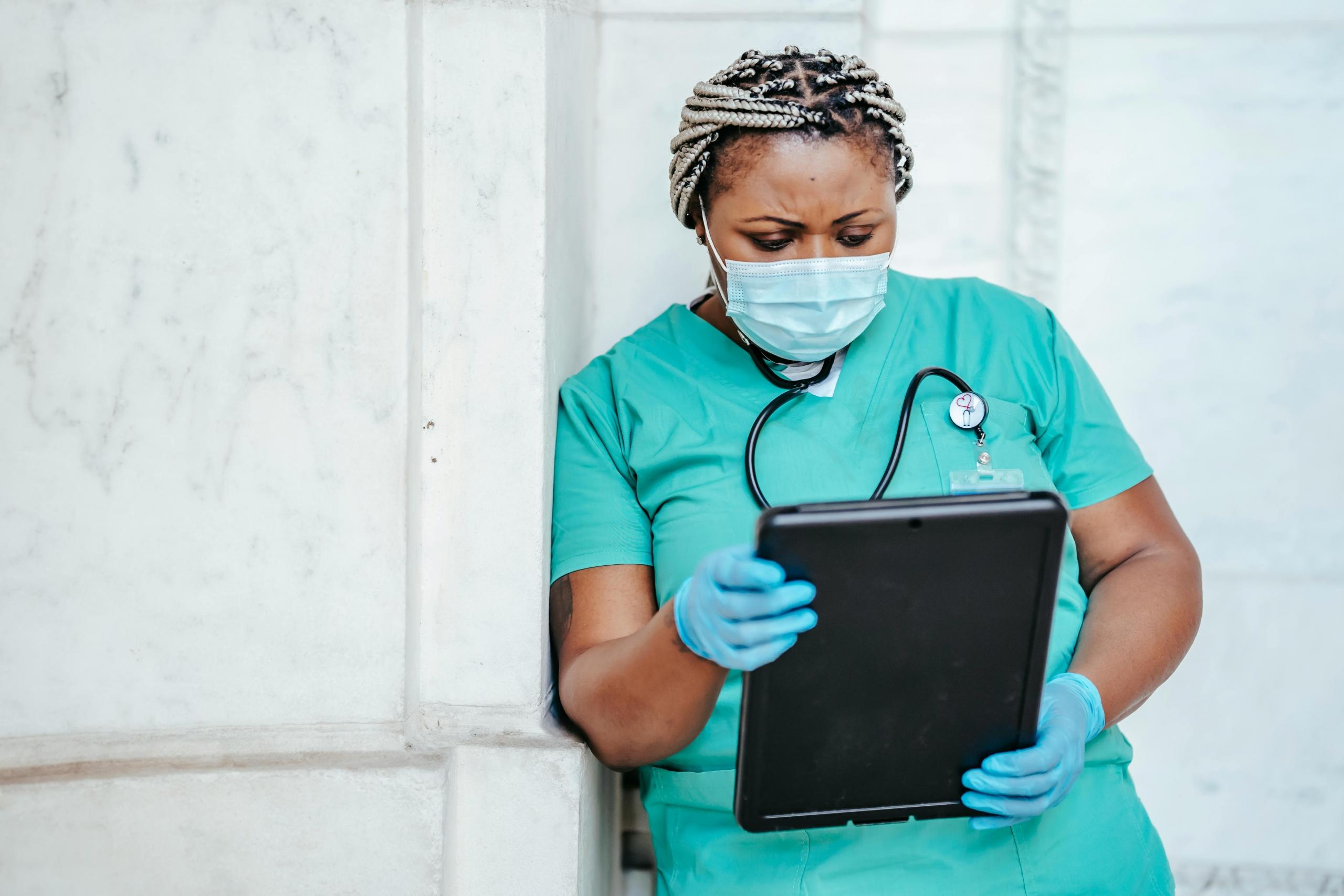 a nurse looks at her notes on a device.