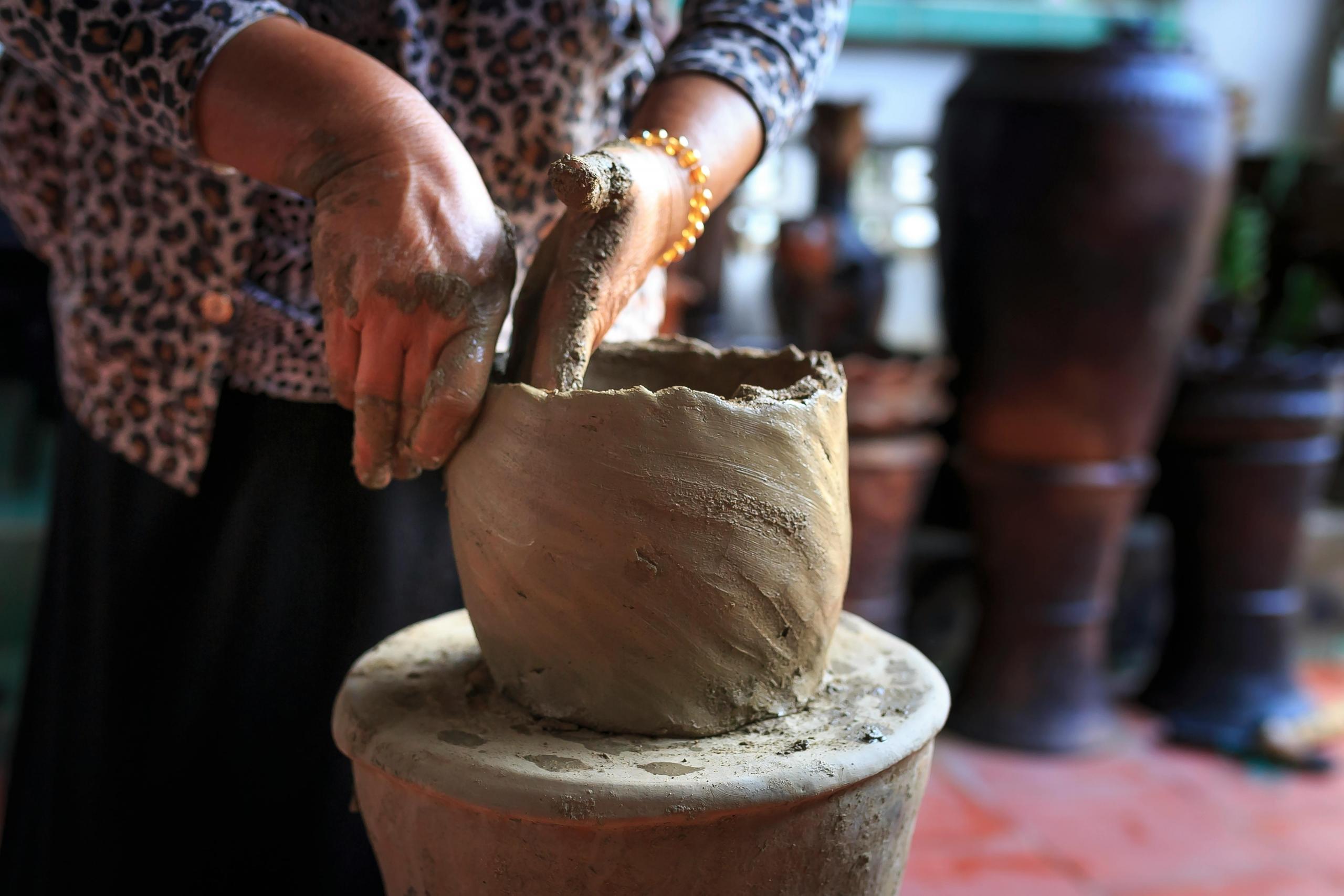 a woman hand builds a large pot.