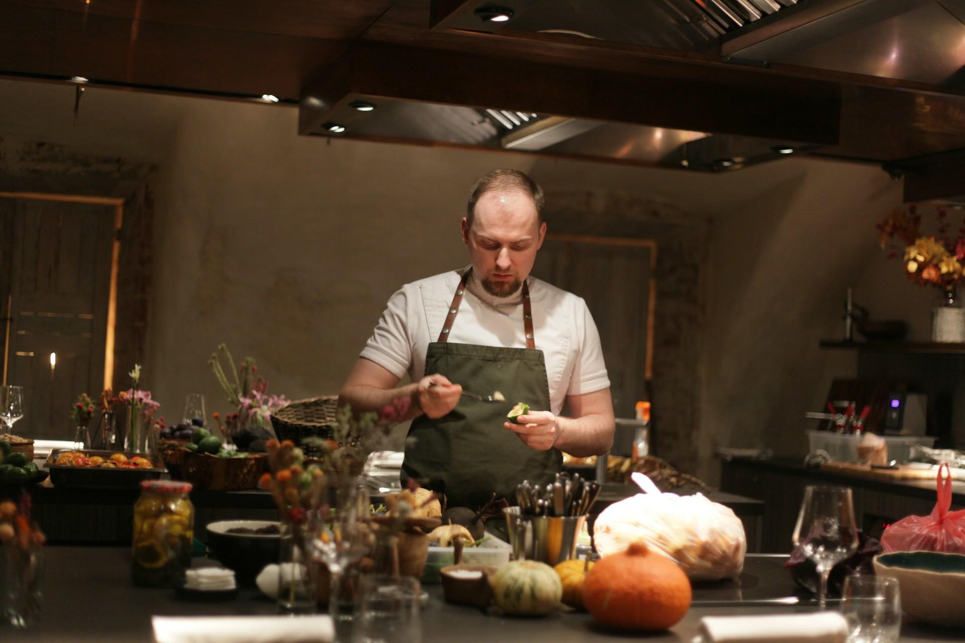 A chef cooking in a kitchen dim lit and surrounded by other ingredients