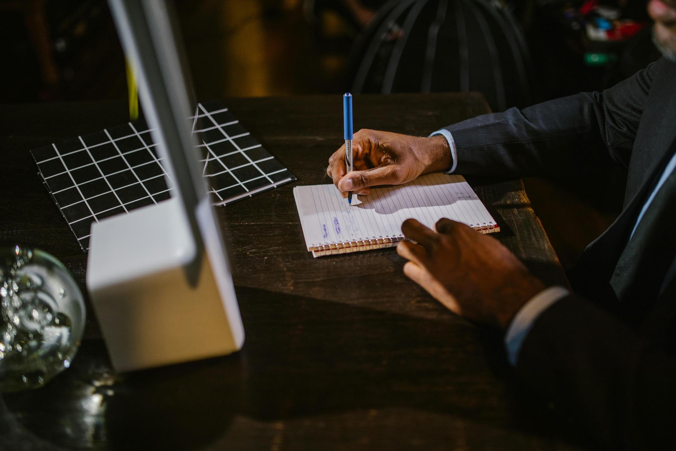 A business professional looks into a monitor, taking notes.