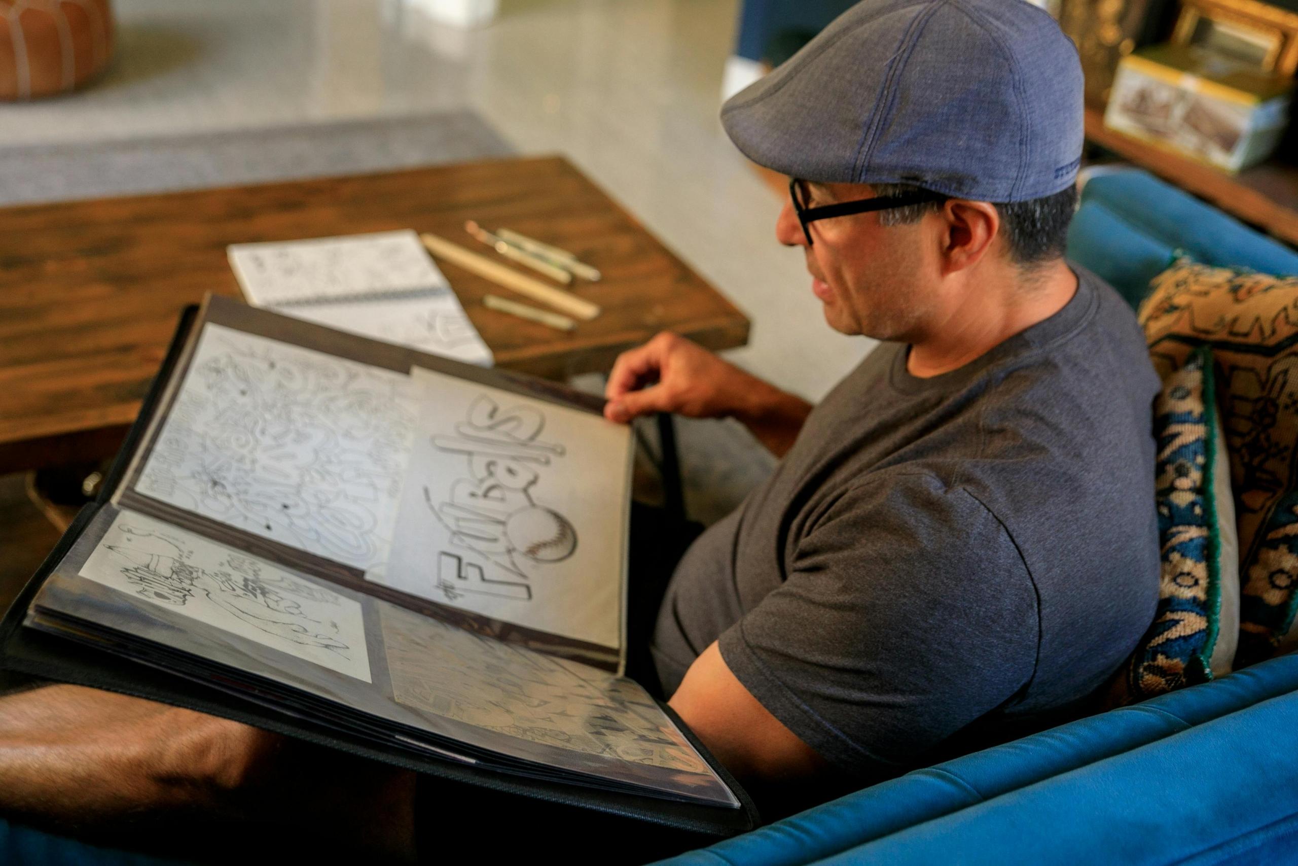 Man looking through a portfolio of drawings and designs.