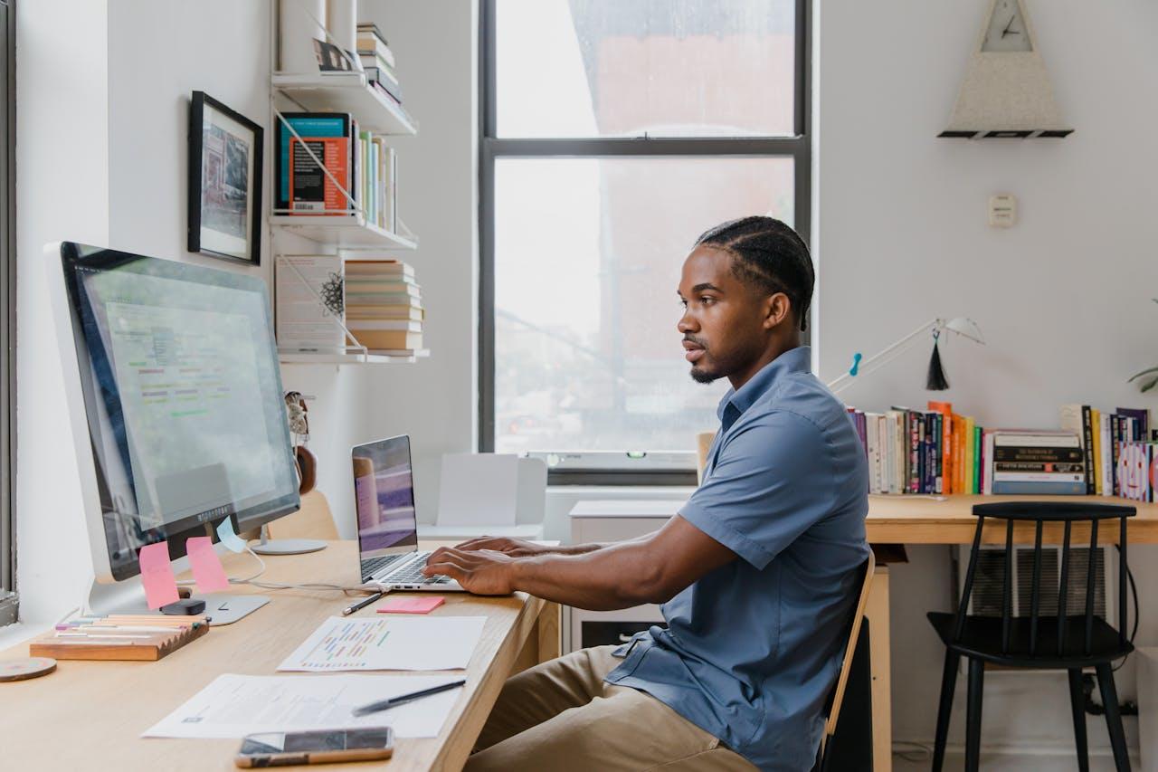 A man sitting at a desk reading code on a desktop computer. 
