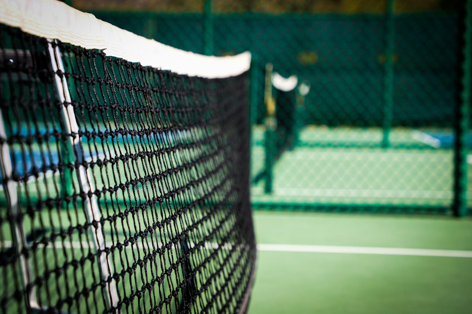 A net in a tennis court where players practice.