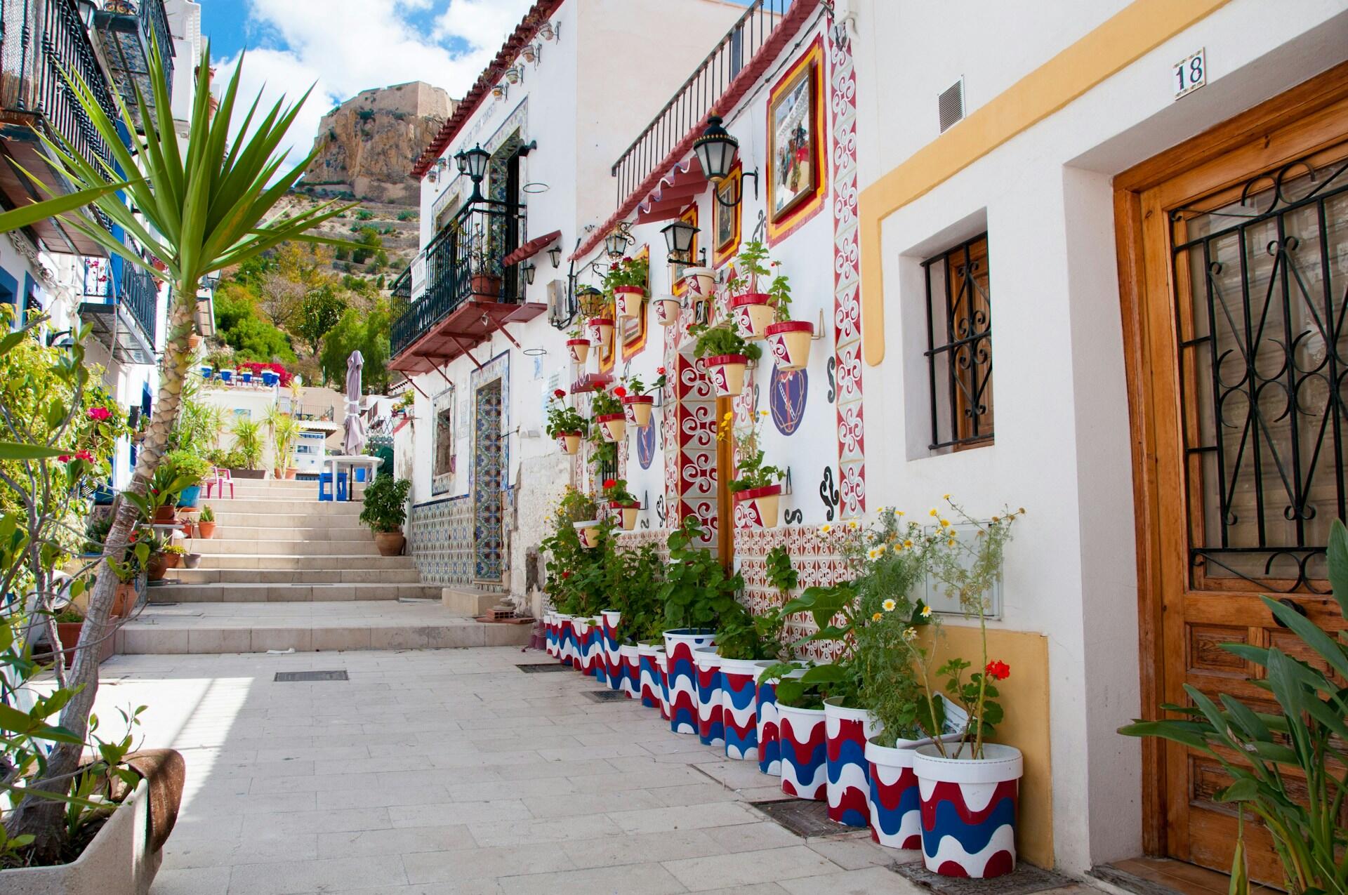 Charming street scene with colorful houses, potted plants, and a staircase leading to a view of a mountain in the background.