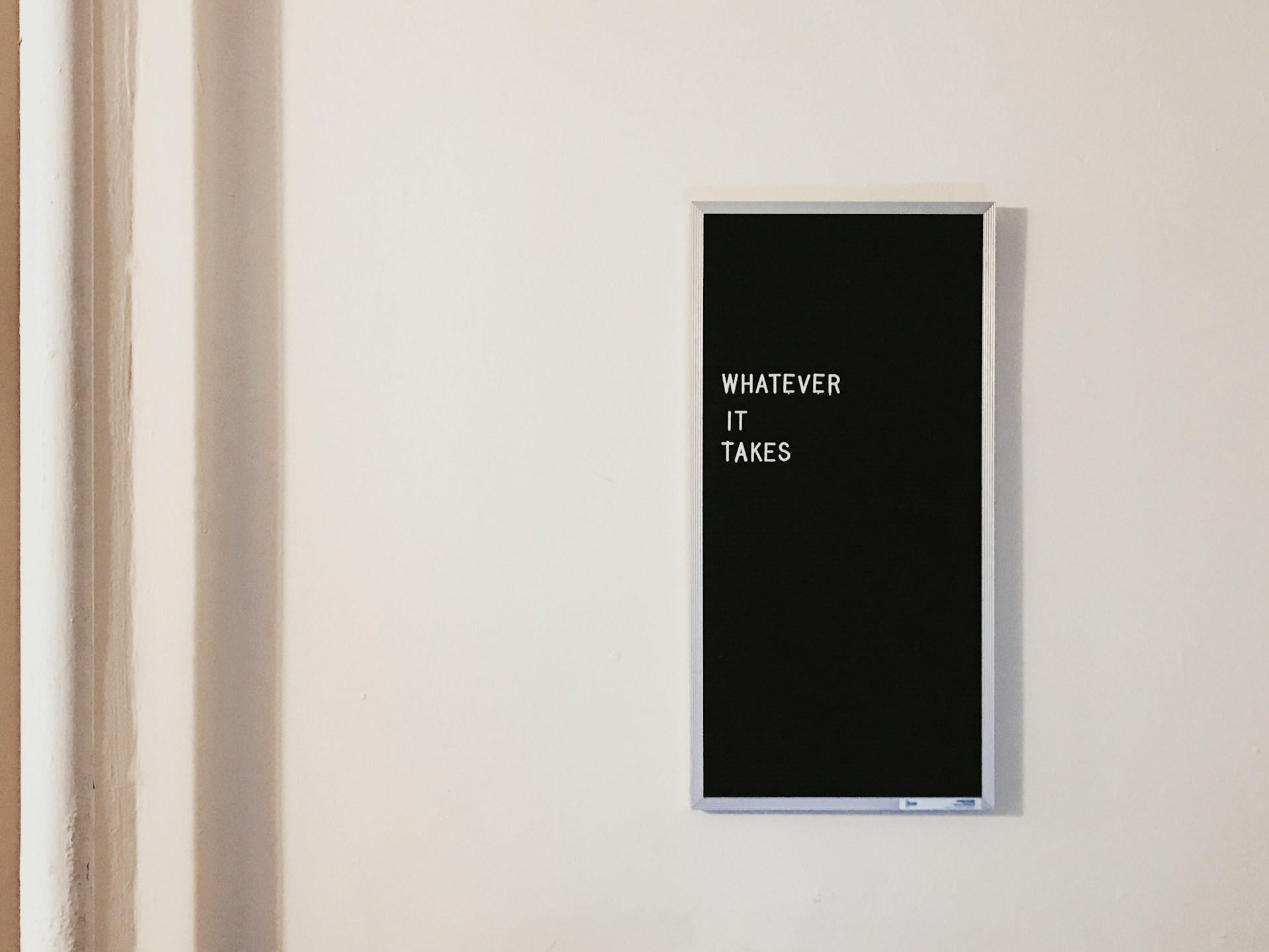 A motivational message on a silver framed blackboard saying "Whatever it takes"