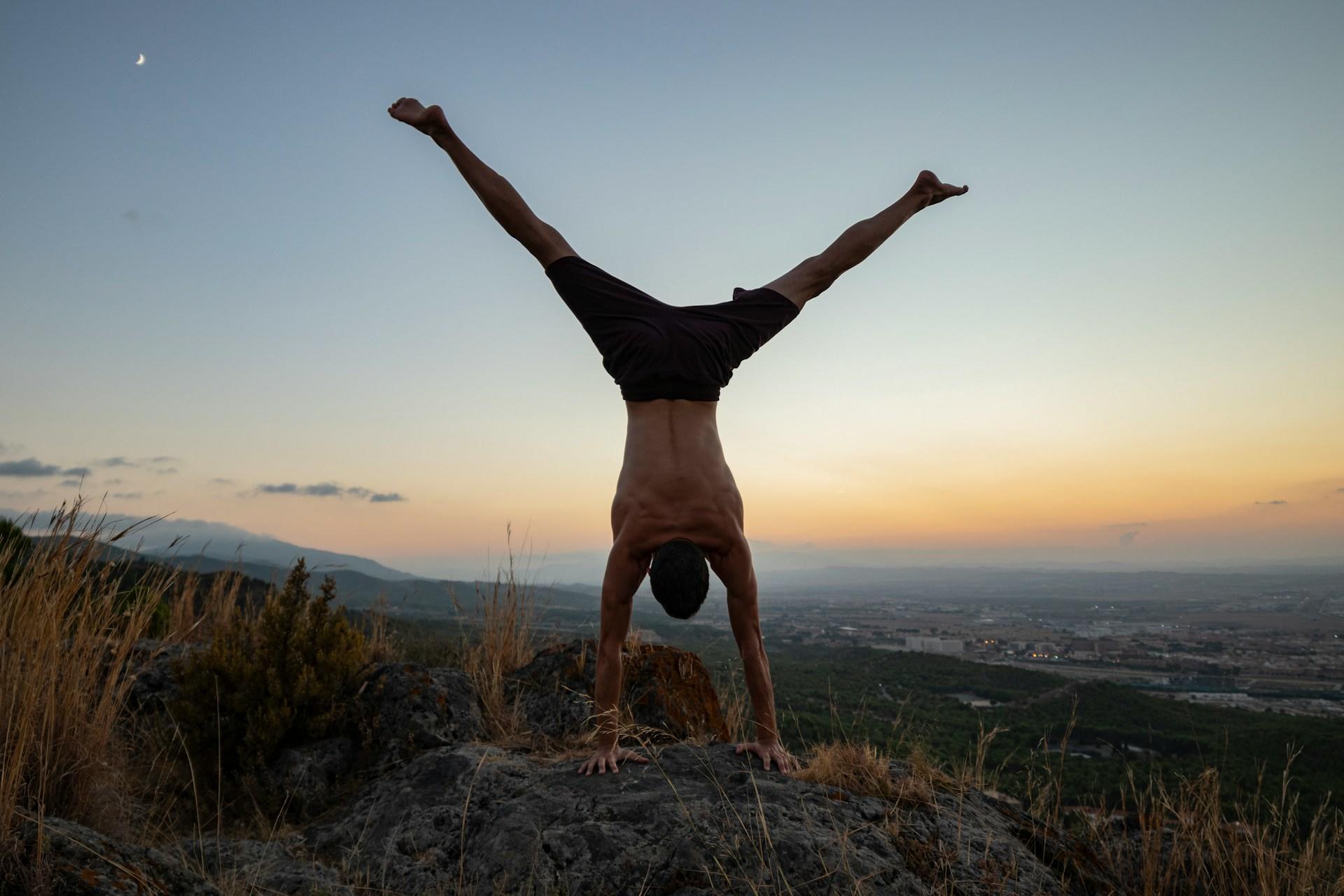 a man doing a hand stand in nature, practising his calisthenics skills