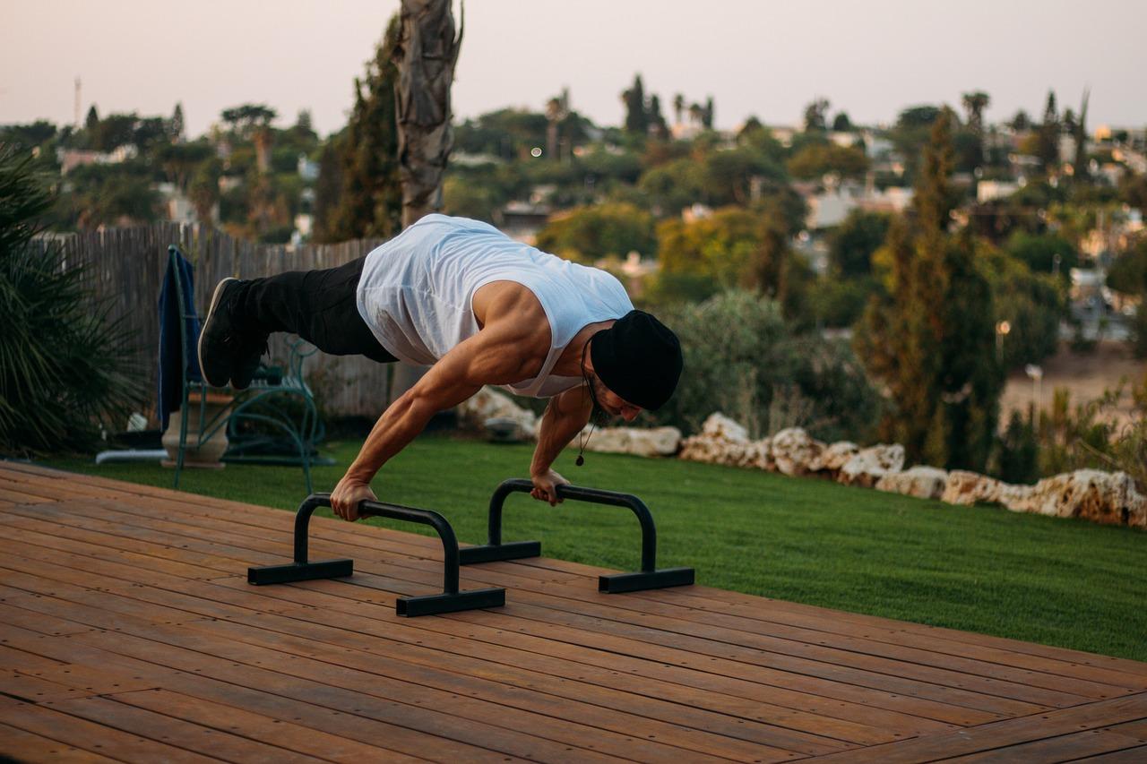 A man lifting his full body on parallel bars as part of his calisthenics workout plan.