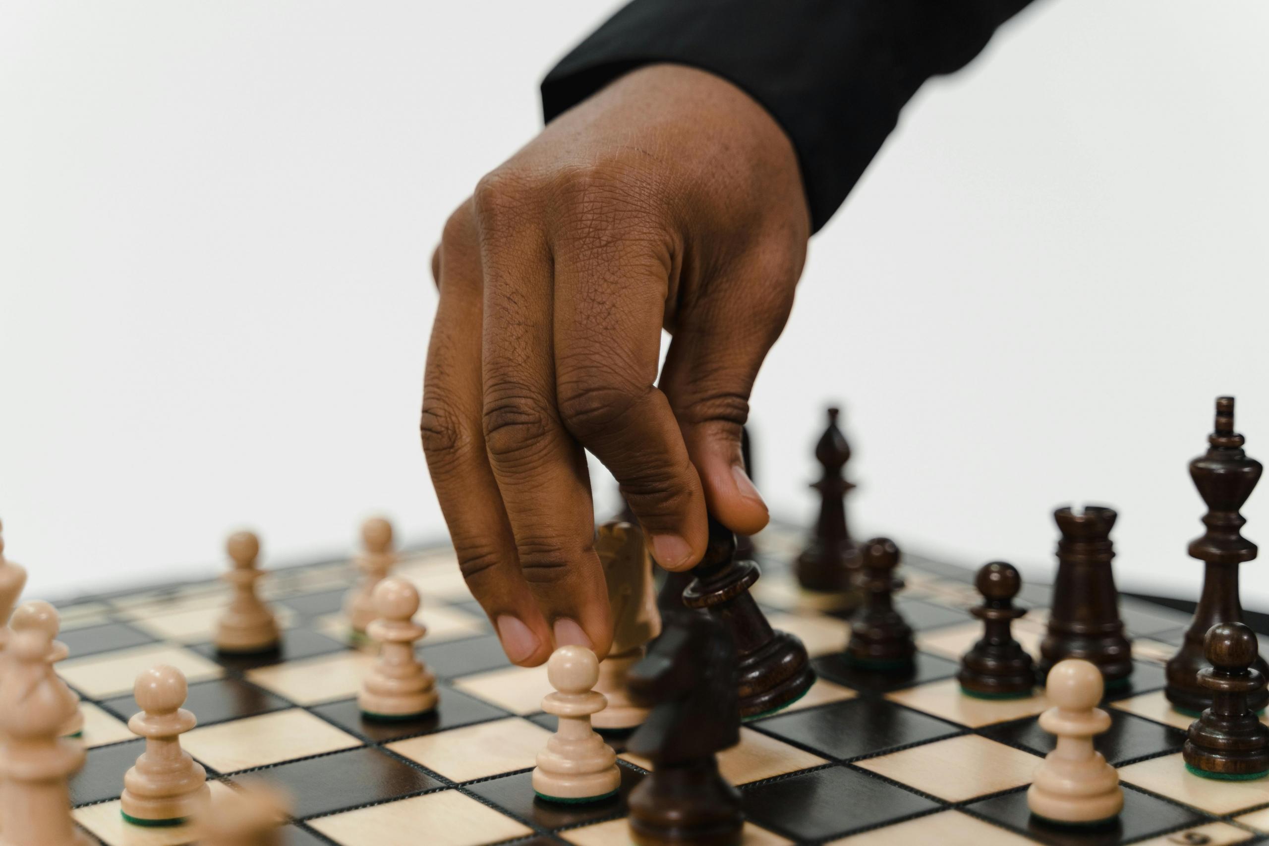 a hand can be seen moving a chess piece on a board.