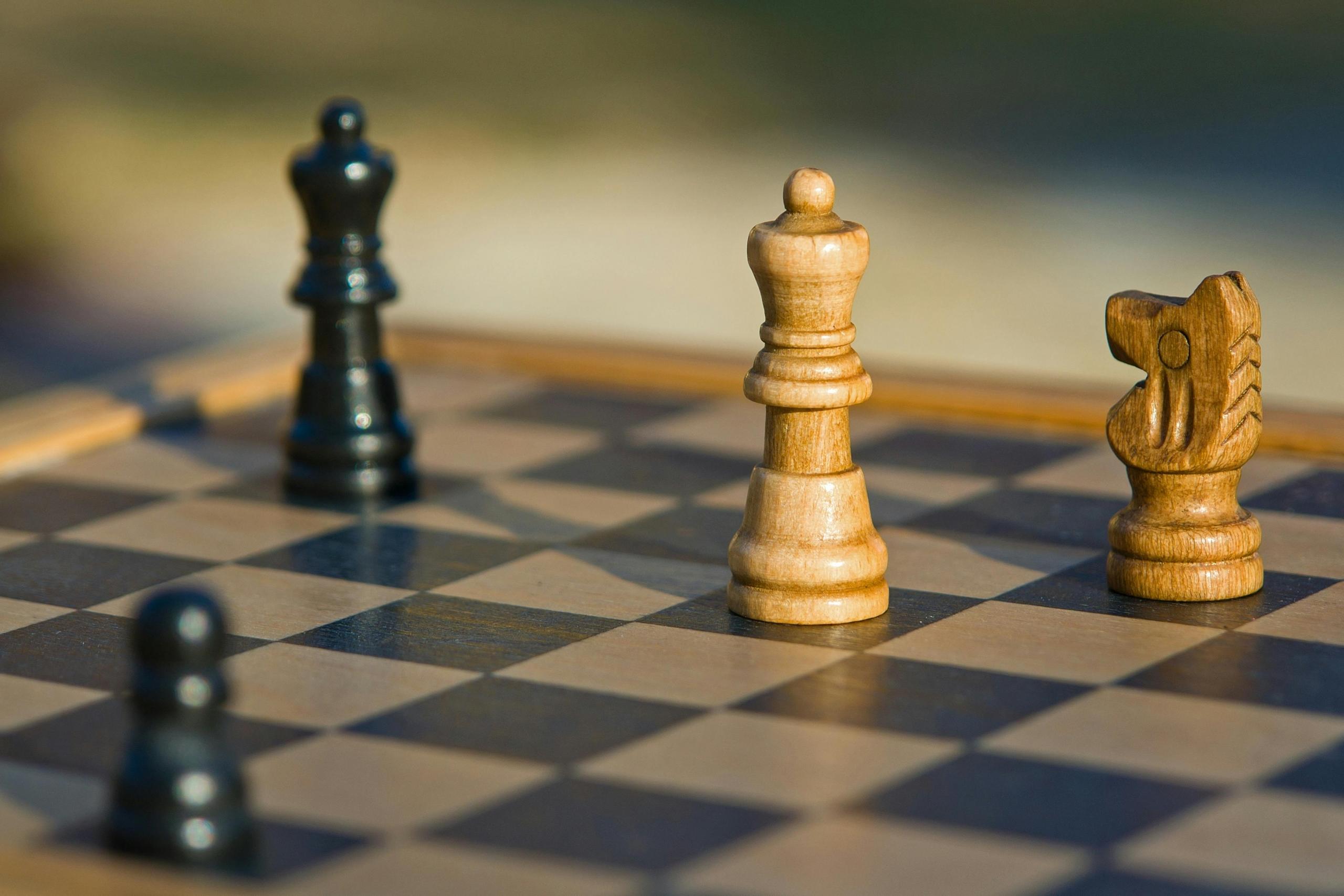 A chess board is empty but for a few valuable pieces left on the board. Two light pieces seem to have the advantage.