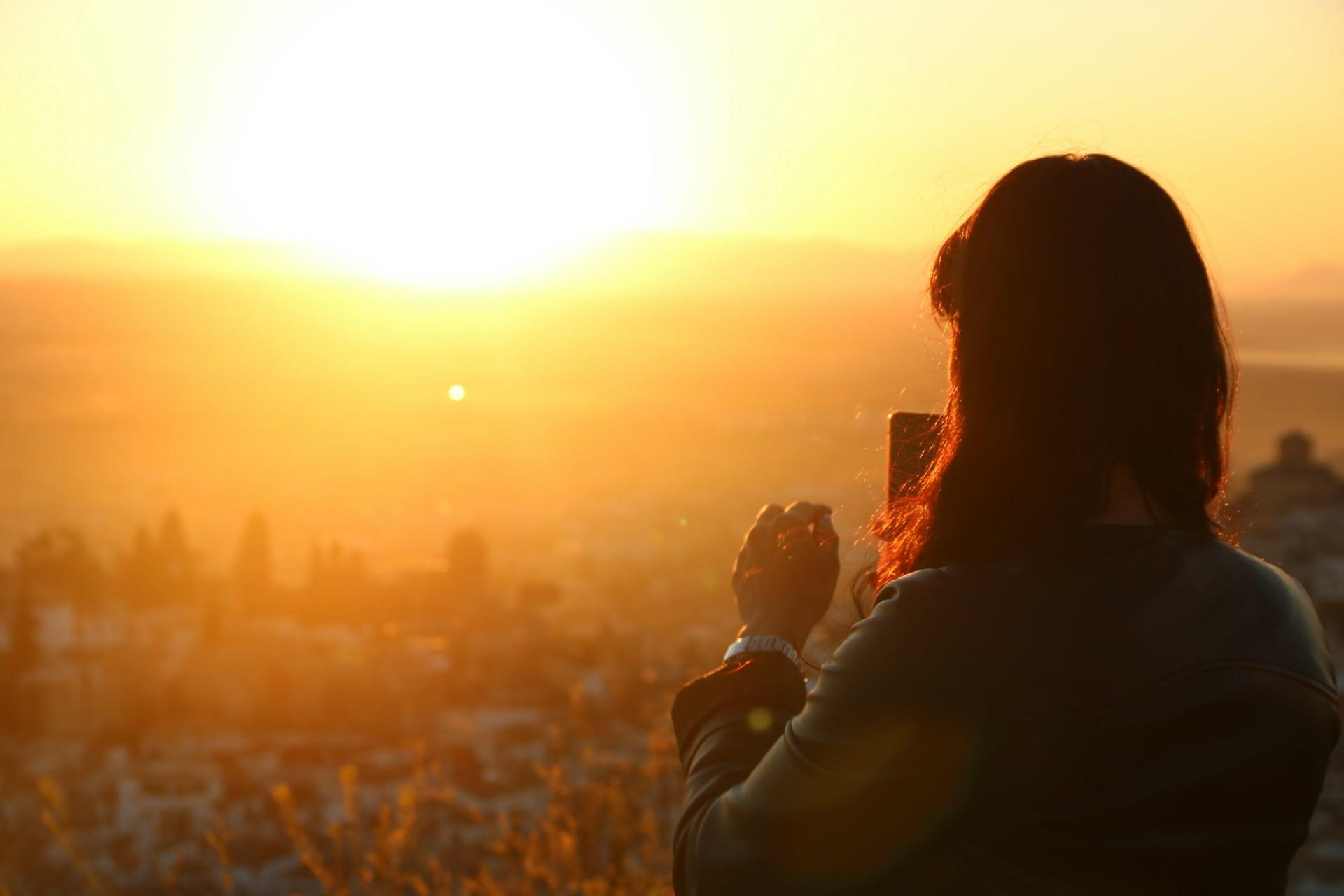 A woman photographing the sunset at the Alhambra in Granada, Spain.