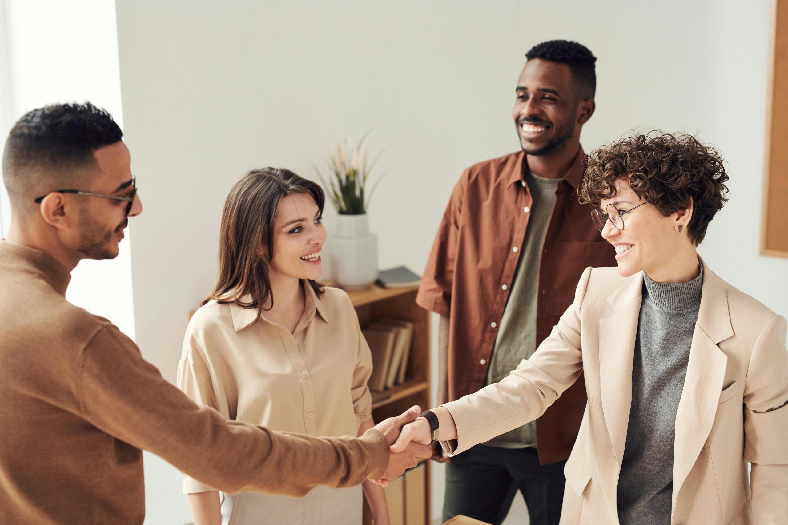 a team of professionals join hands in a show of teamwork. They are indoors in a room with white walls.