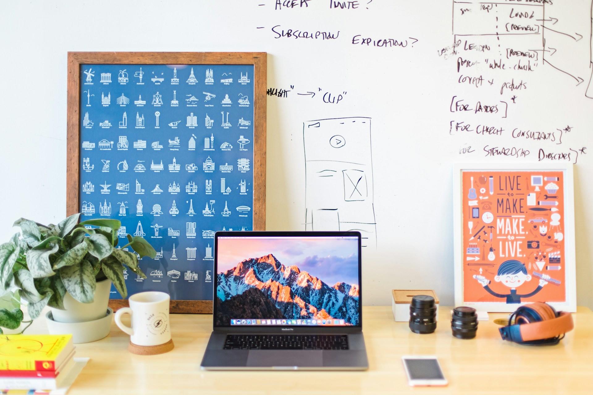 A laptop on top of a table together with merchandise and posters  they made with their Graphic design course.