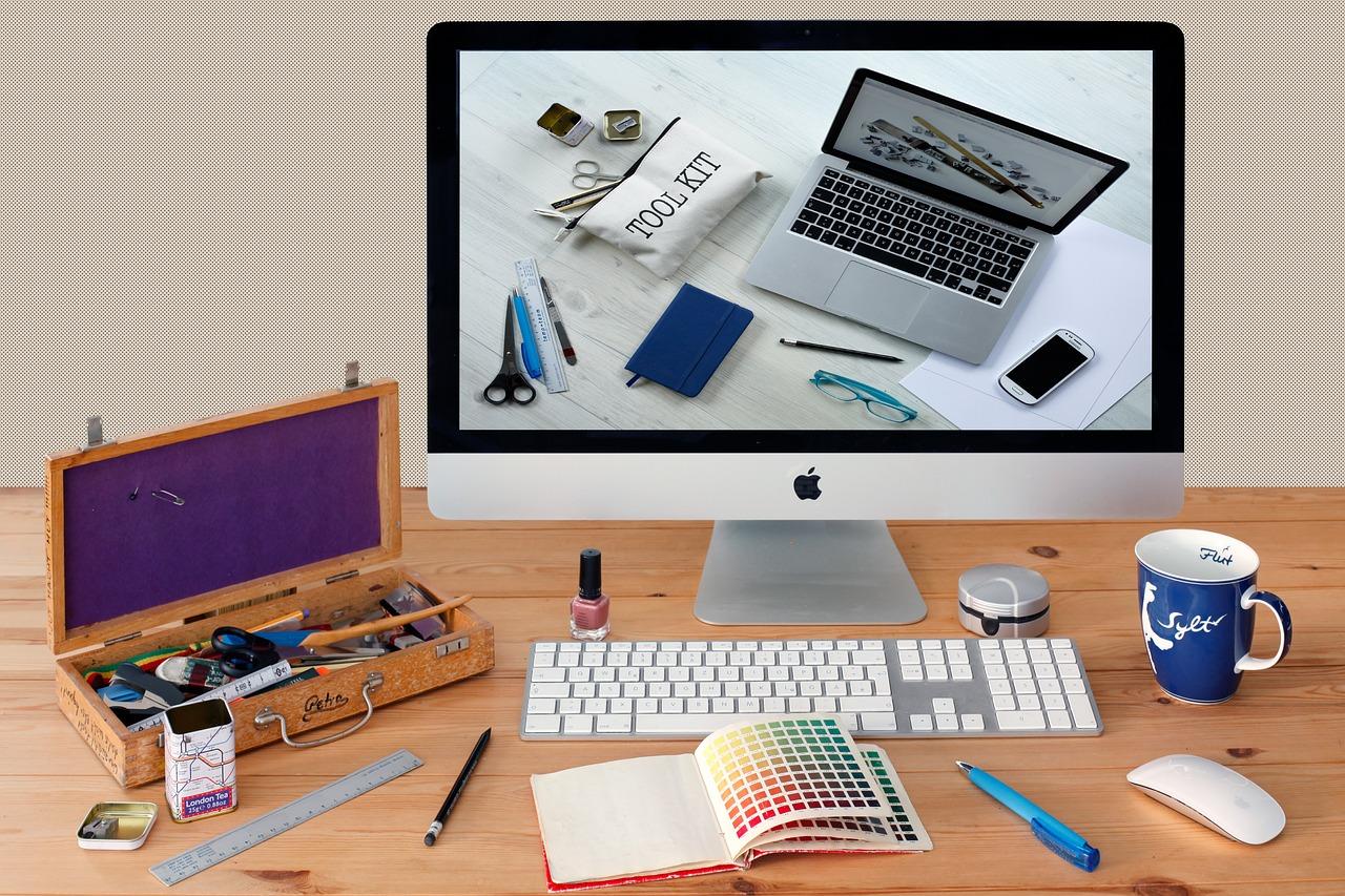 A computer on a table with other art supplies for graphic design.