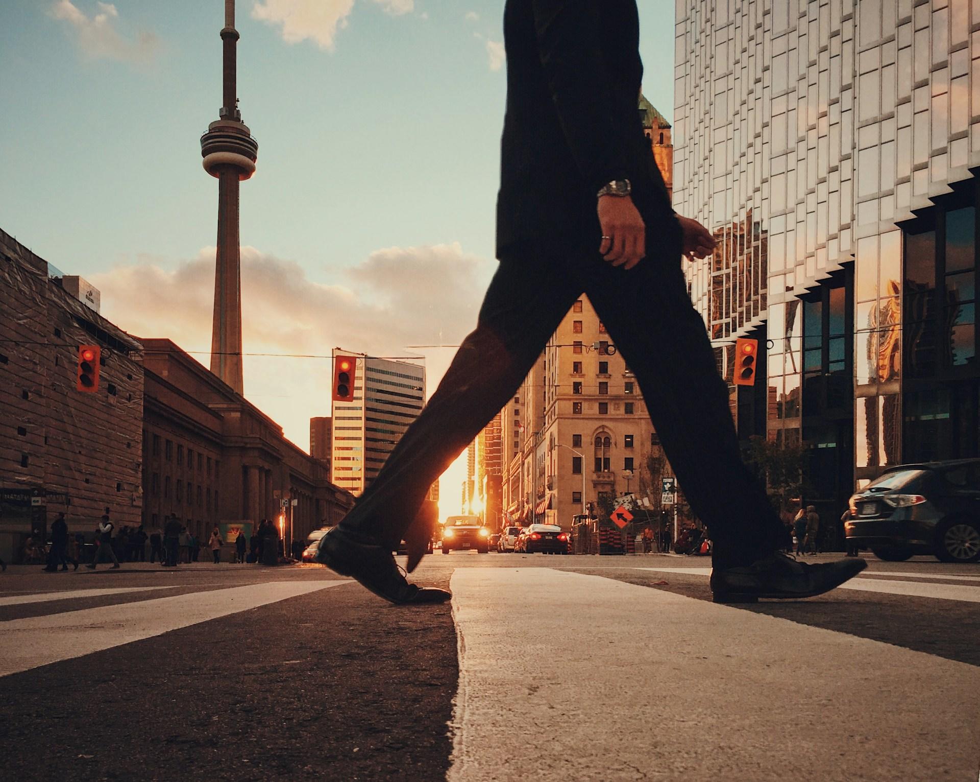 A man crossing the street in Toronto on his way to a Graphic Design class.