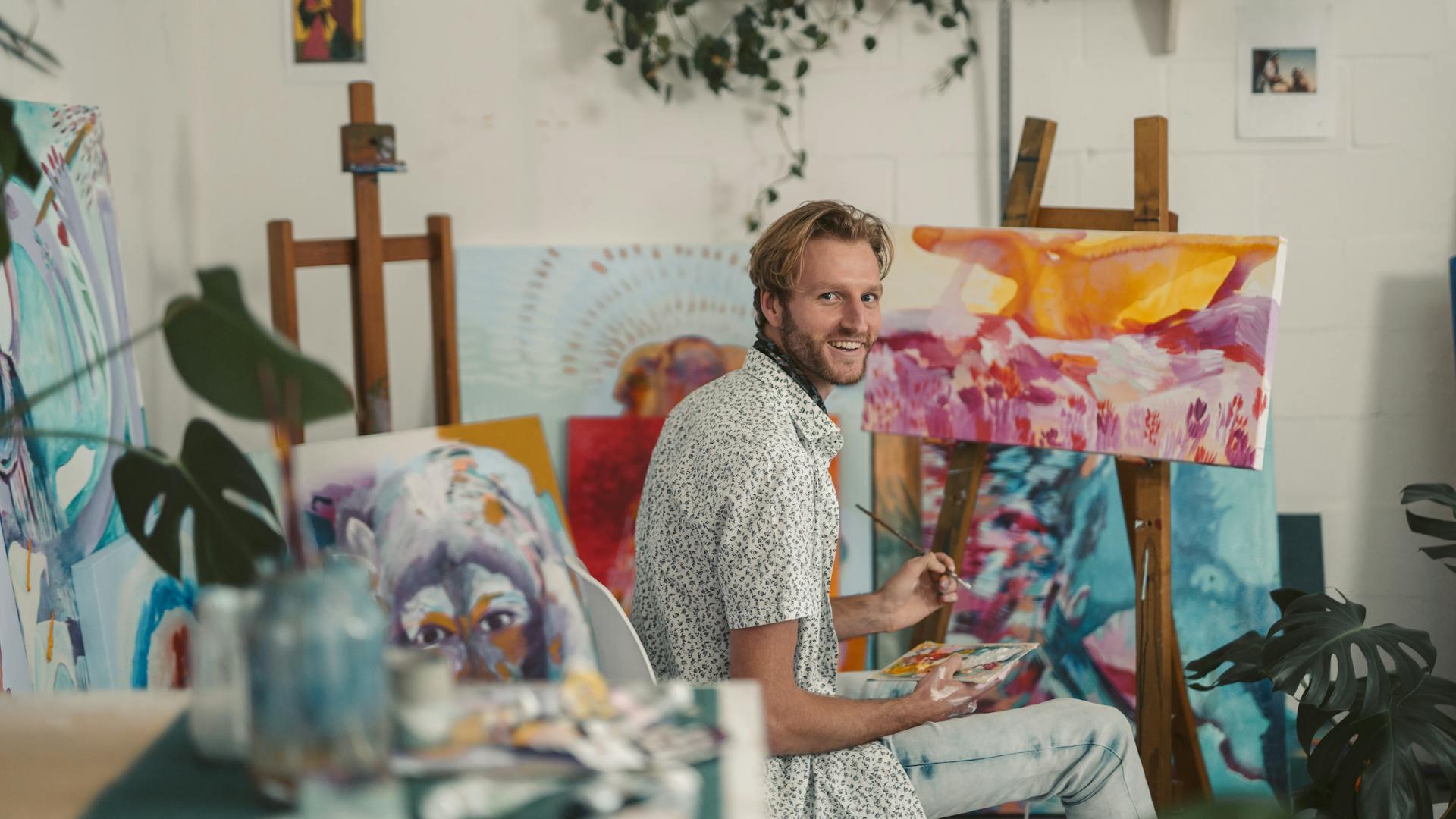 A man painting in a colorful art studio.