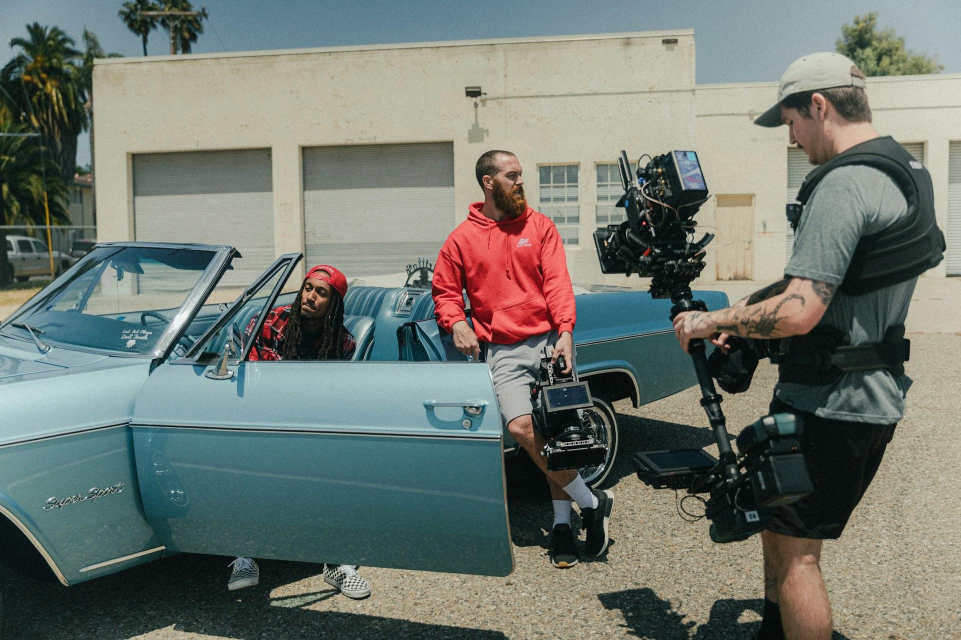 Two men acting and one recording the scene in a parking lot