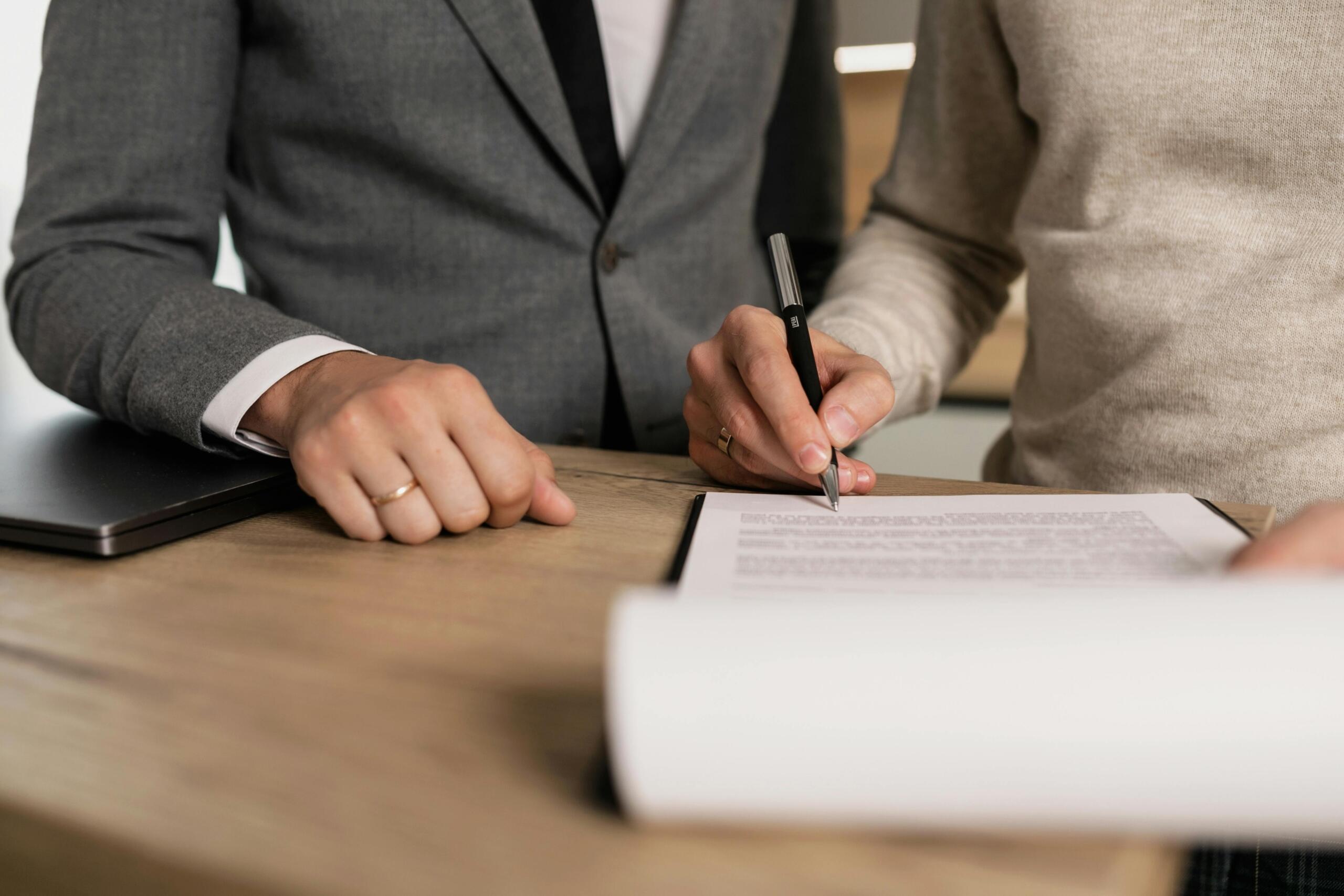 Two people signing a legal document at a desk.