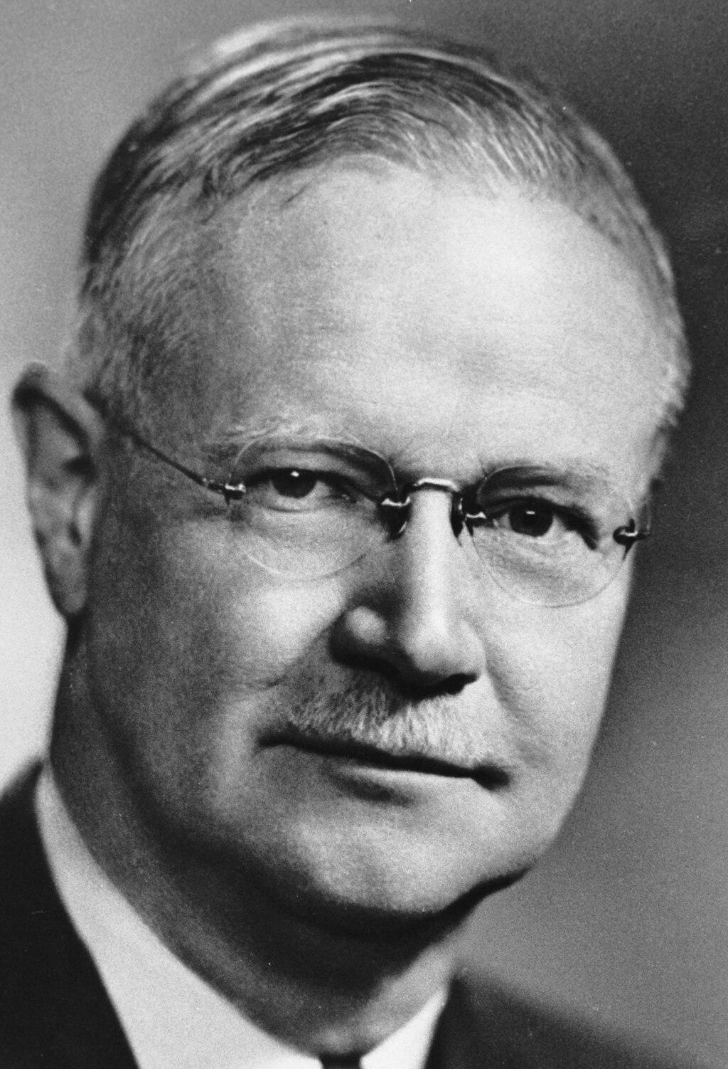A black and white photo of Frederick Tisdall. He wears glasses and smiles slightly at the camera.