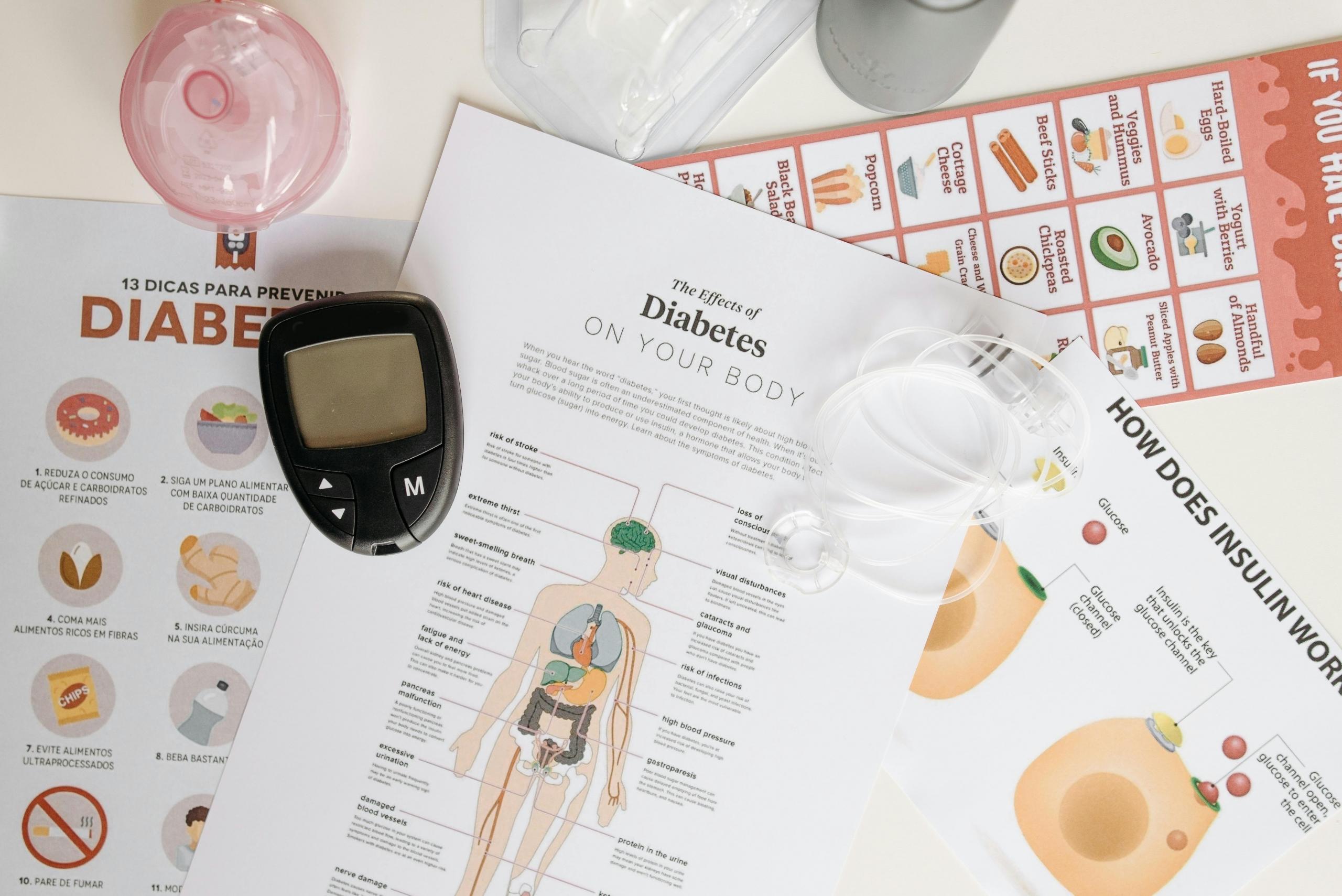 a table covered in diabetes related diagrams and information. A blood sugar testing device is on the table.