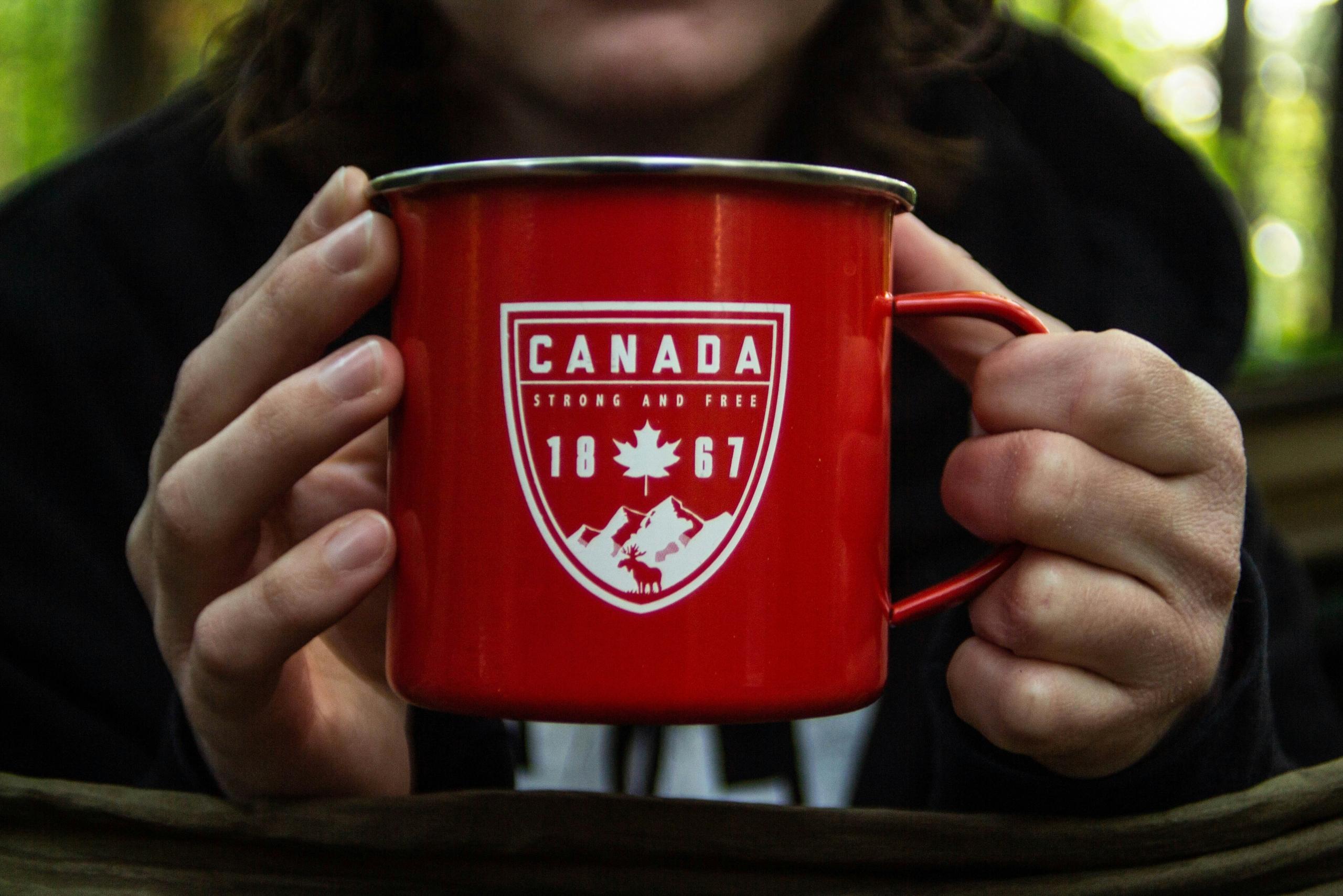 A person holding a red mug with the text 