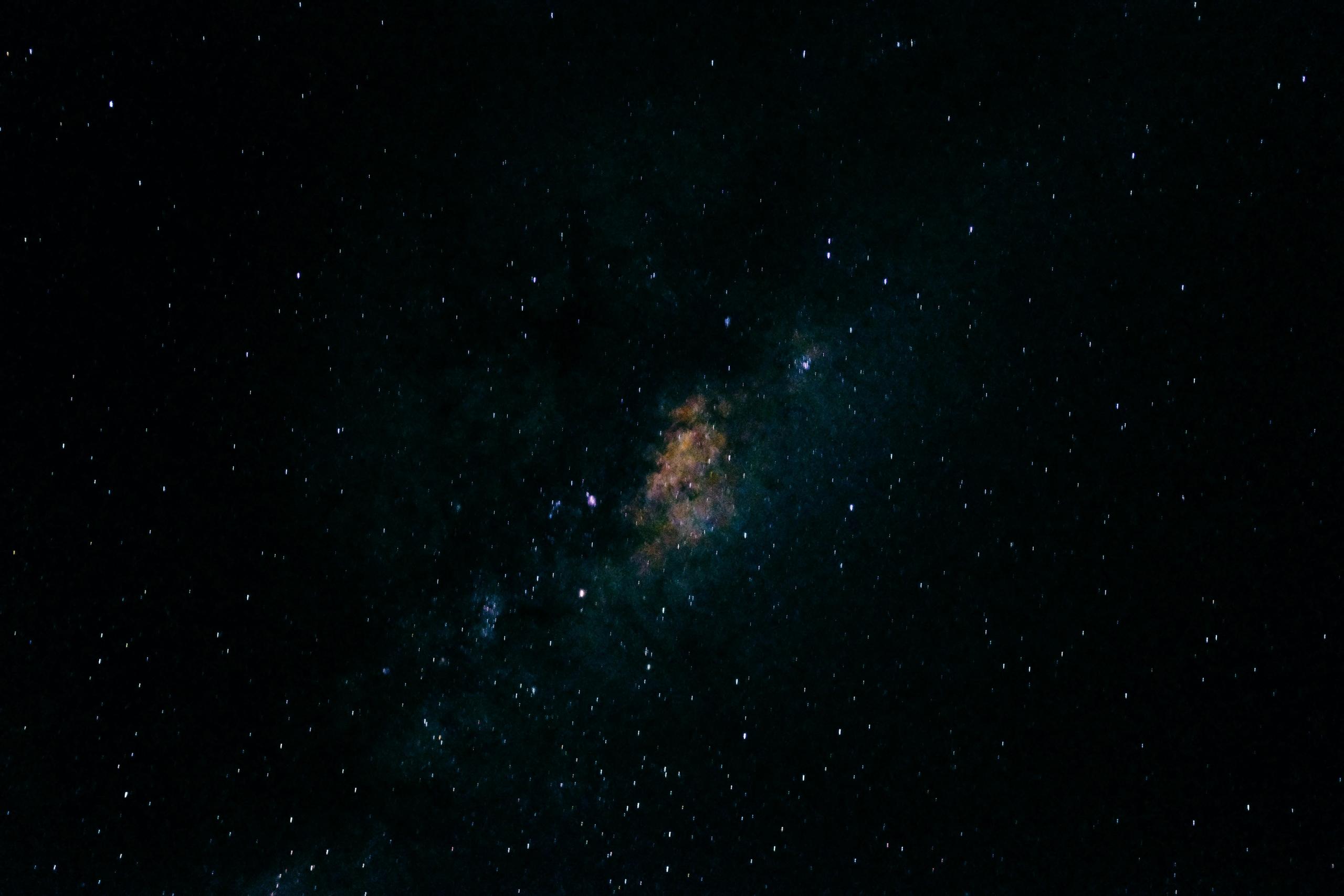 A photo of the stars in space with a light coloured splotch at the middle.