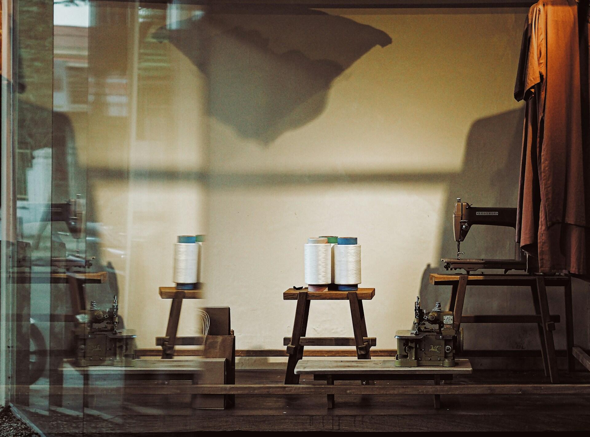 A window scene featuring a sewing machine on a table beside a chair, creating a cozy crafting space.