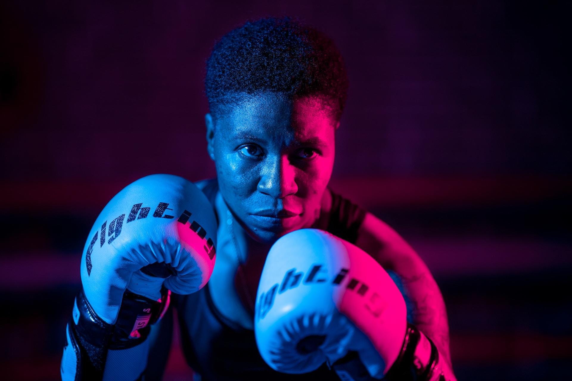A woman boxer wearing boxing gloves ready to fight.