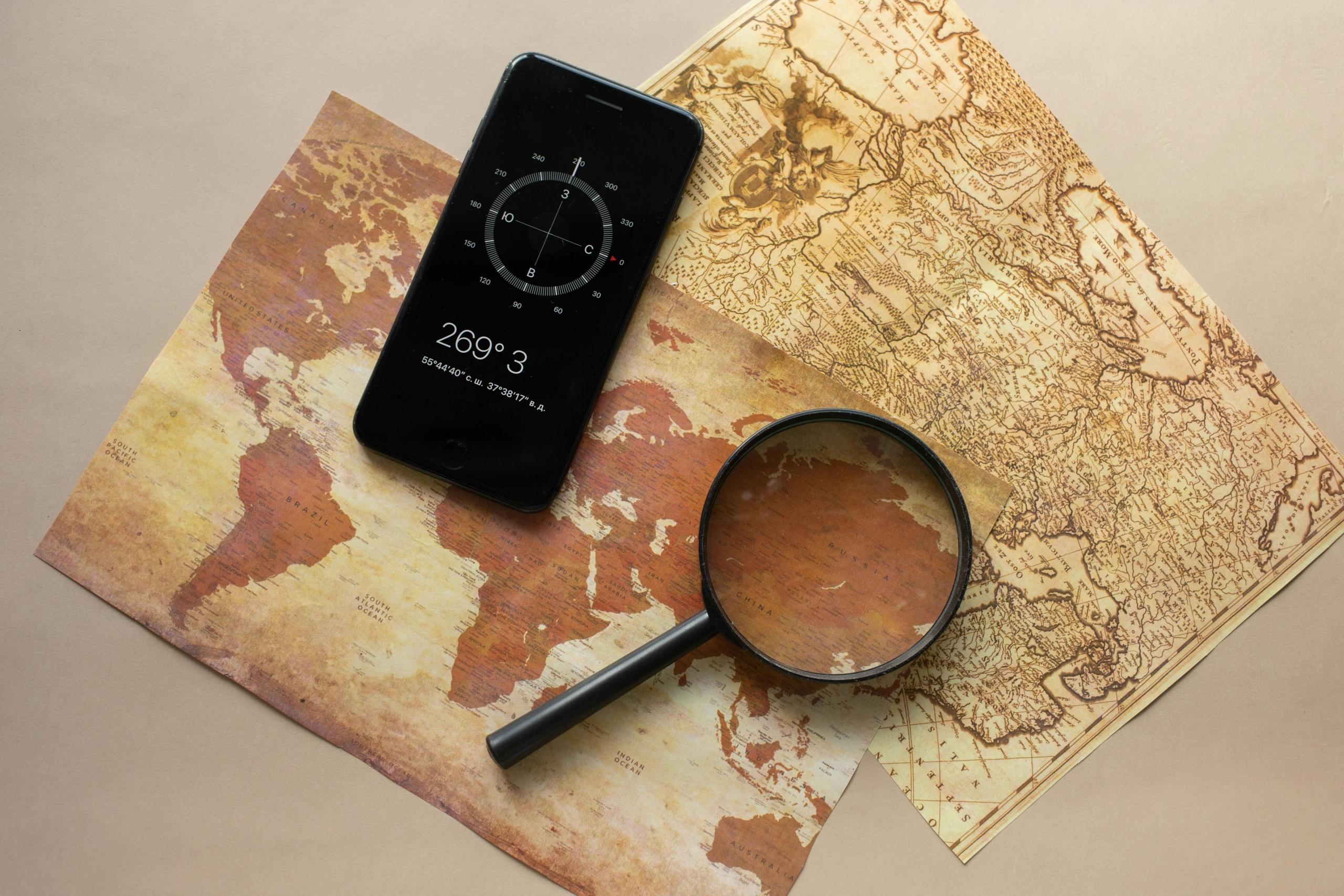A world map laying on the table with a compass and magnifying glass.