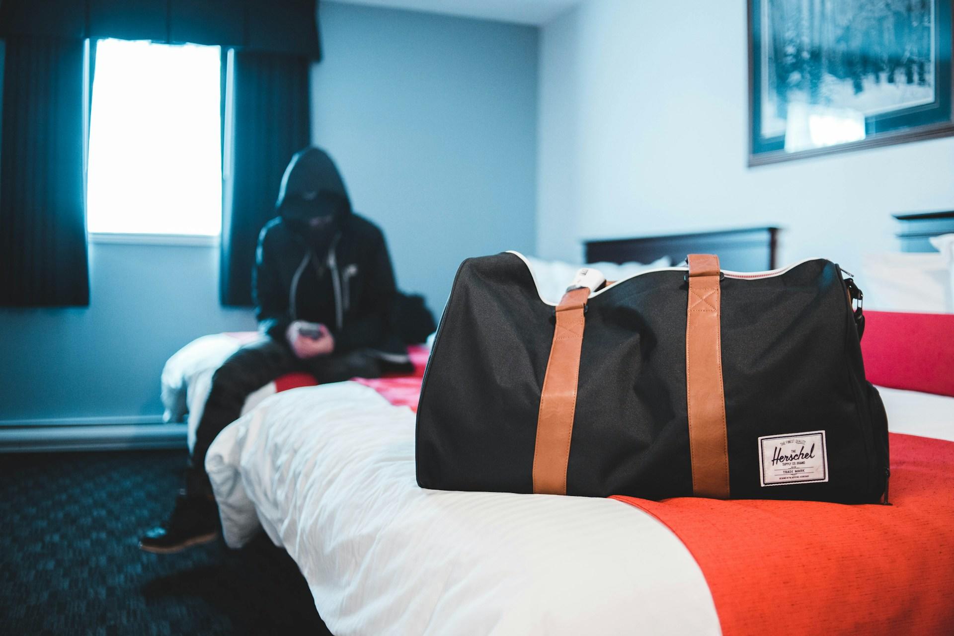 a student sitting on bed with a luggage. 