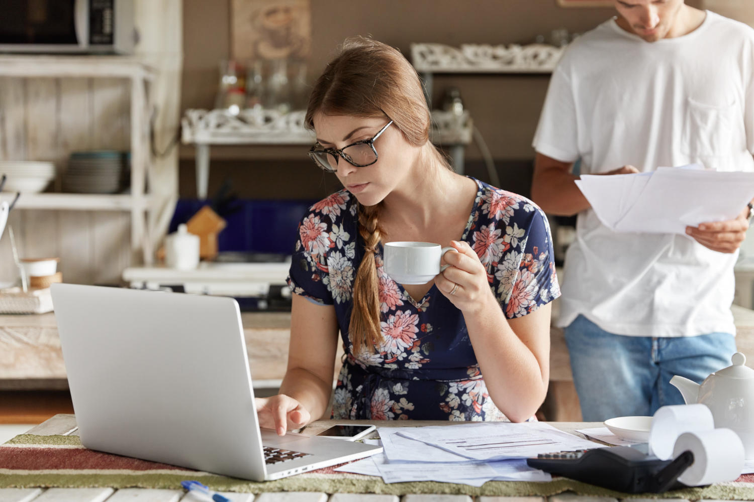 a couple looking at documents while facing the laptop.