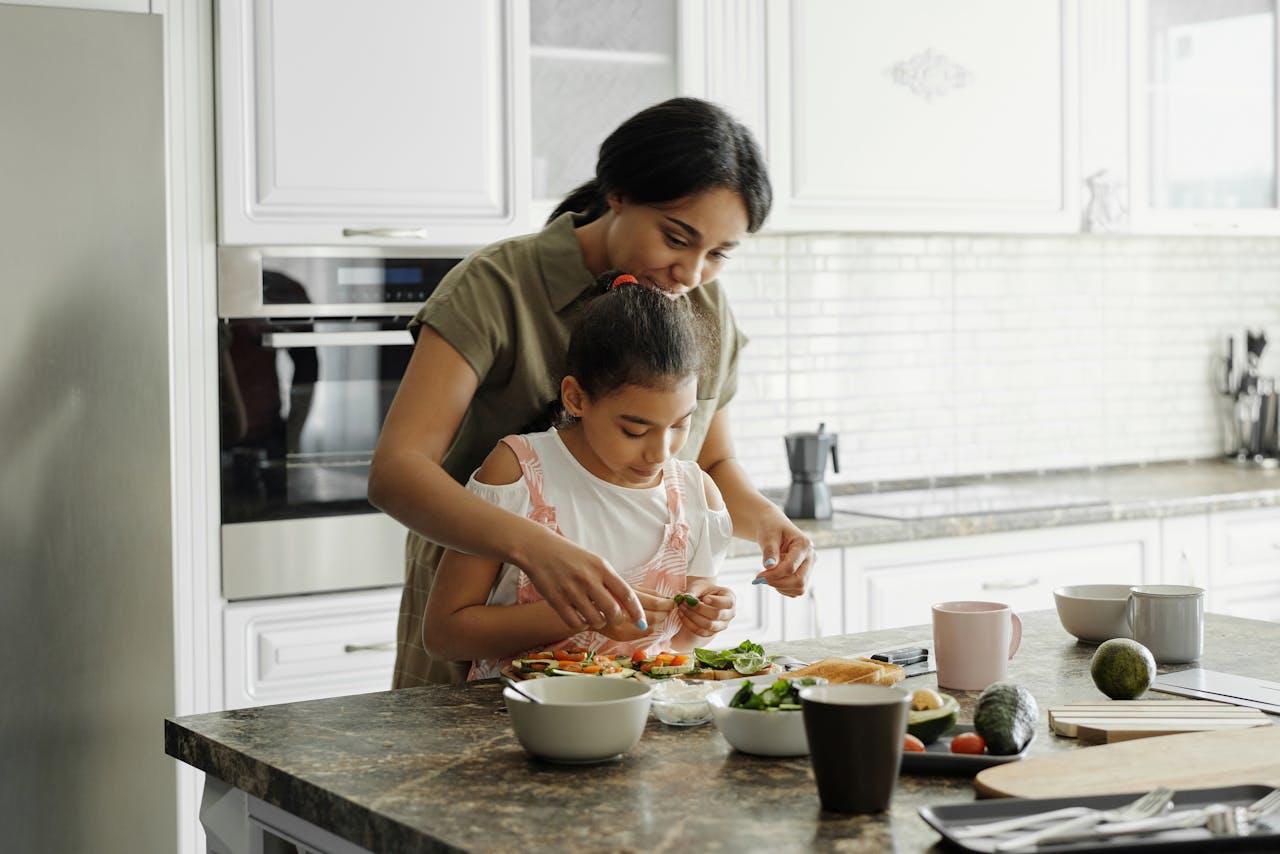 A mother helping her daughter cook in the kitchen.