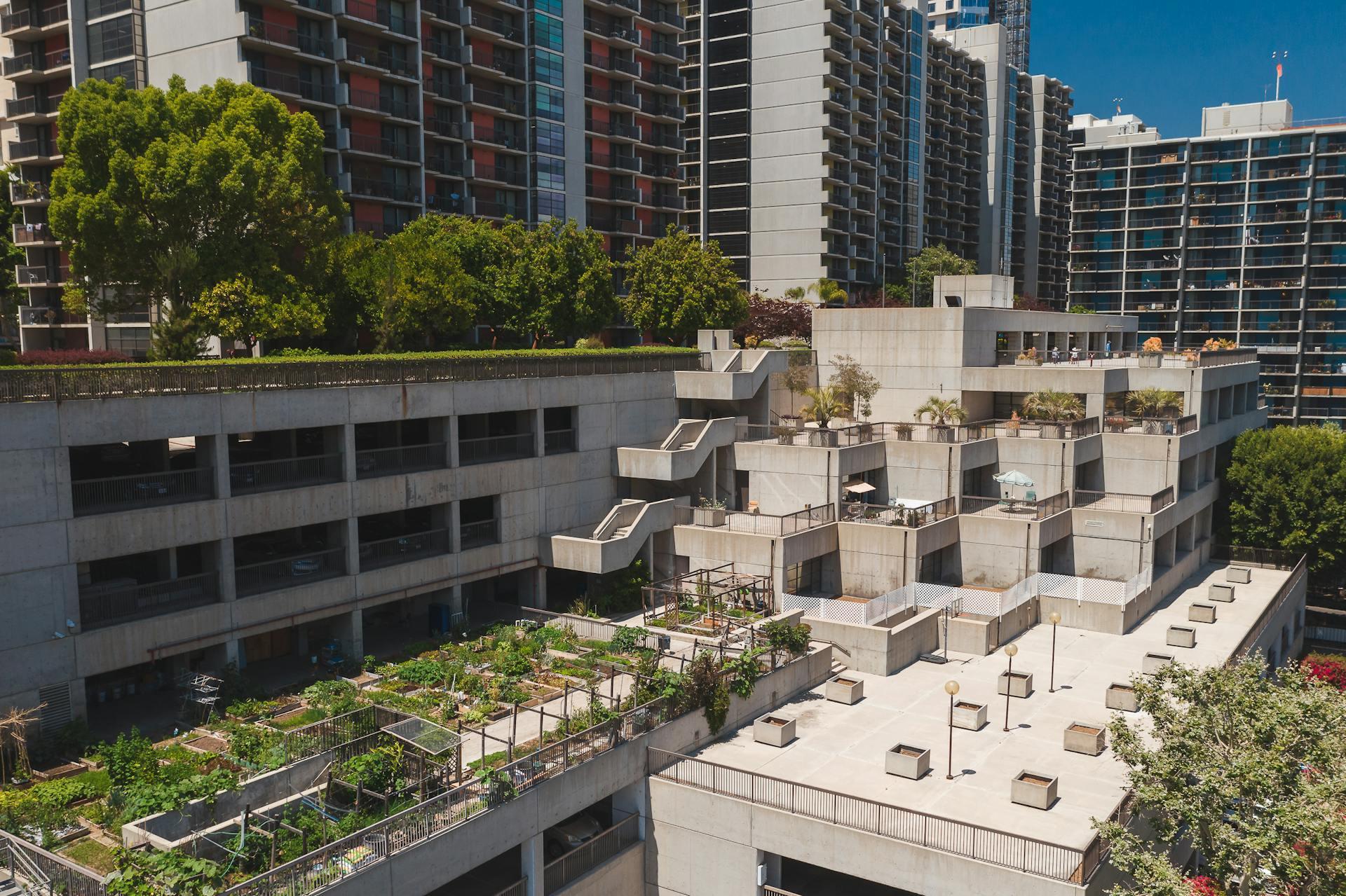 White Concrete Building Near Green Roofs and Trees.