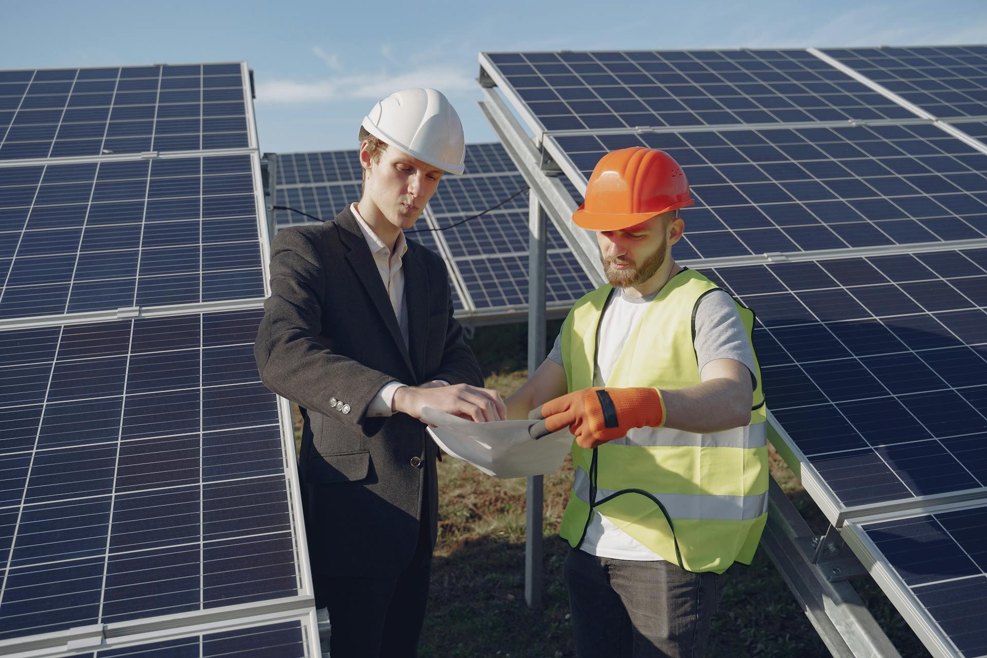 Photo Showing two Electricians Inspecting the Solar Panels.