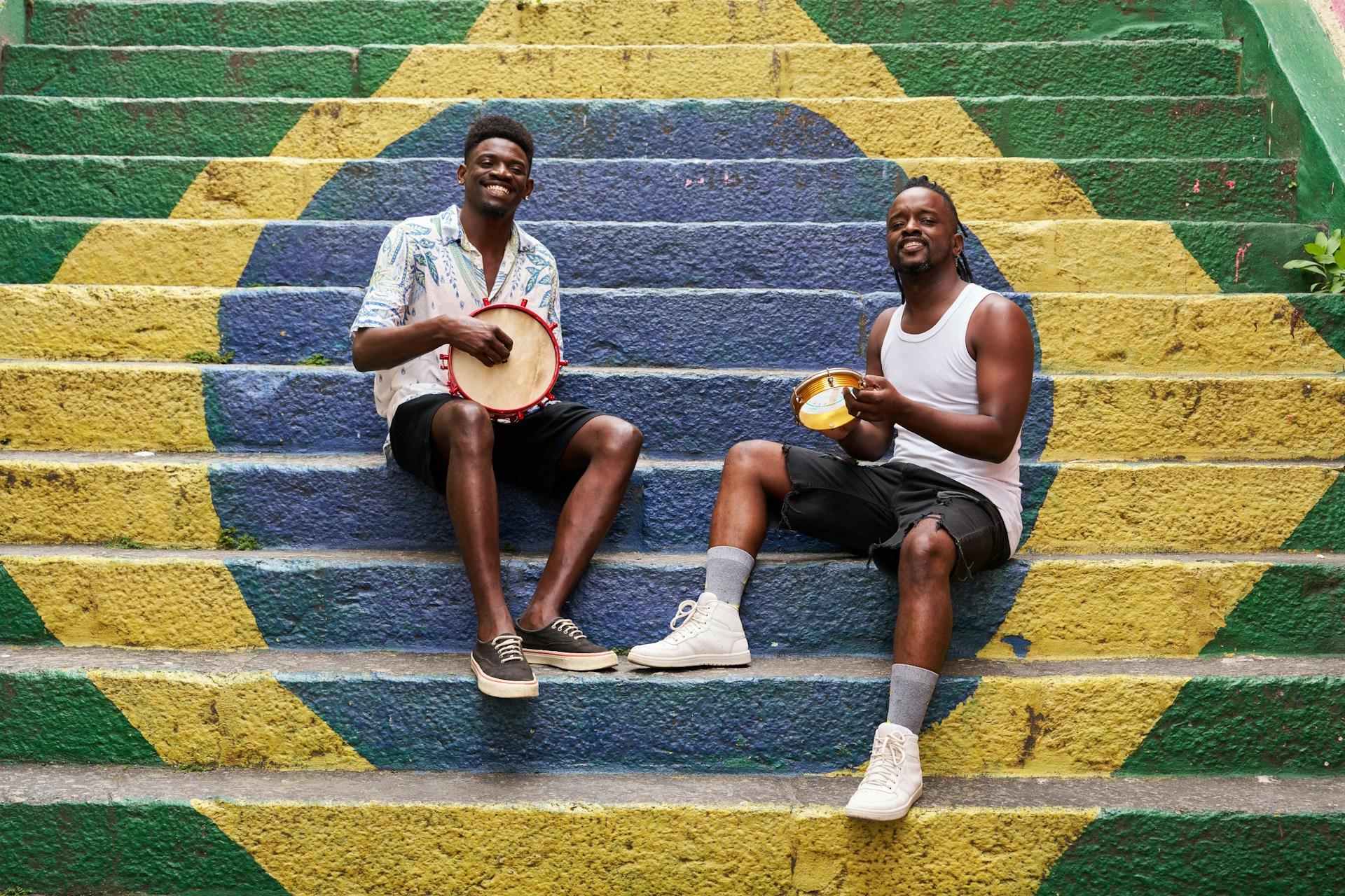 Two individuals playing music on steps colored with the brazilian flag.