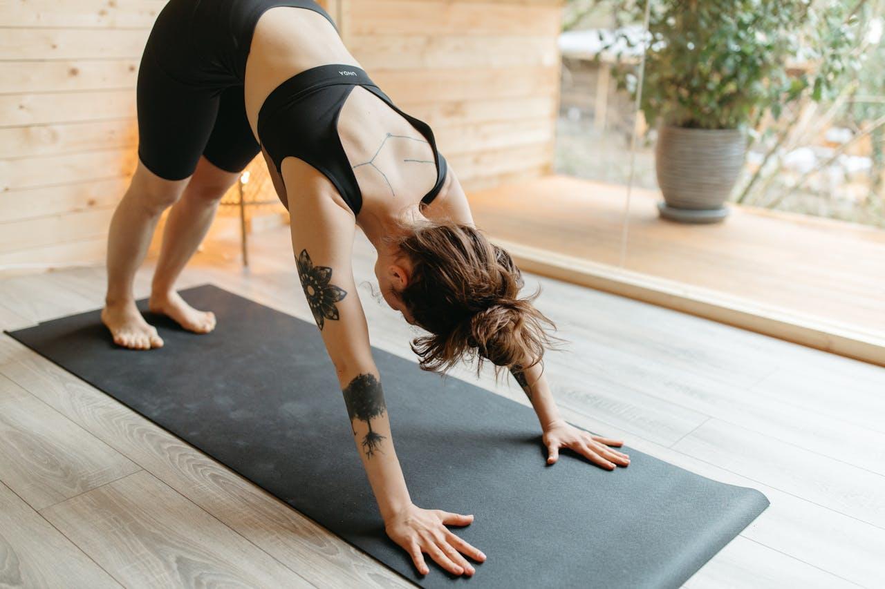 A women doing downward dog on a black yoga matt. 