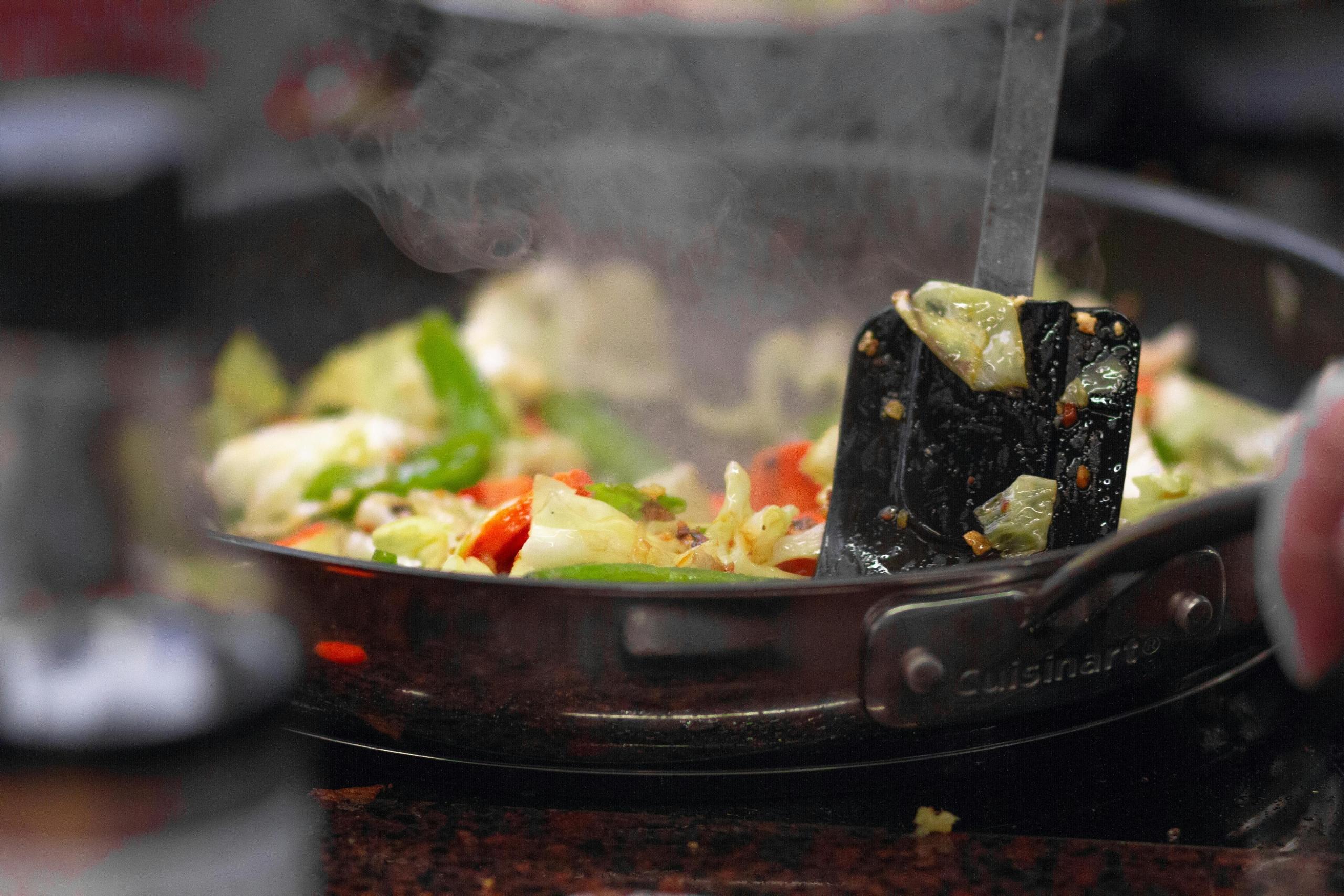 a person stir fries vegetables in a pan.