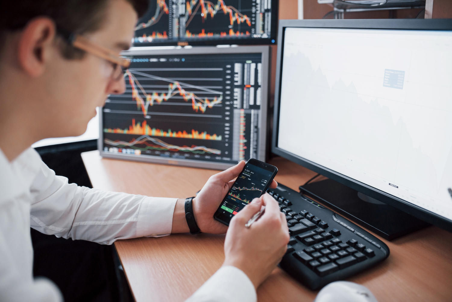 a man looking at screens with trading and stock details.