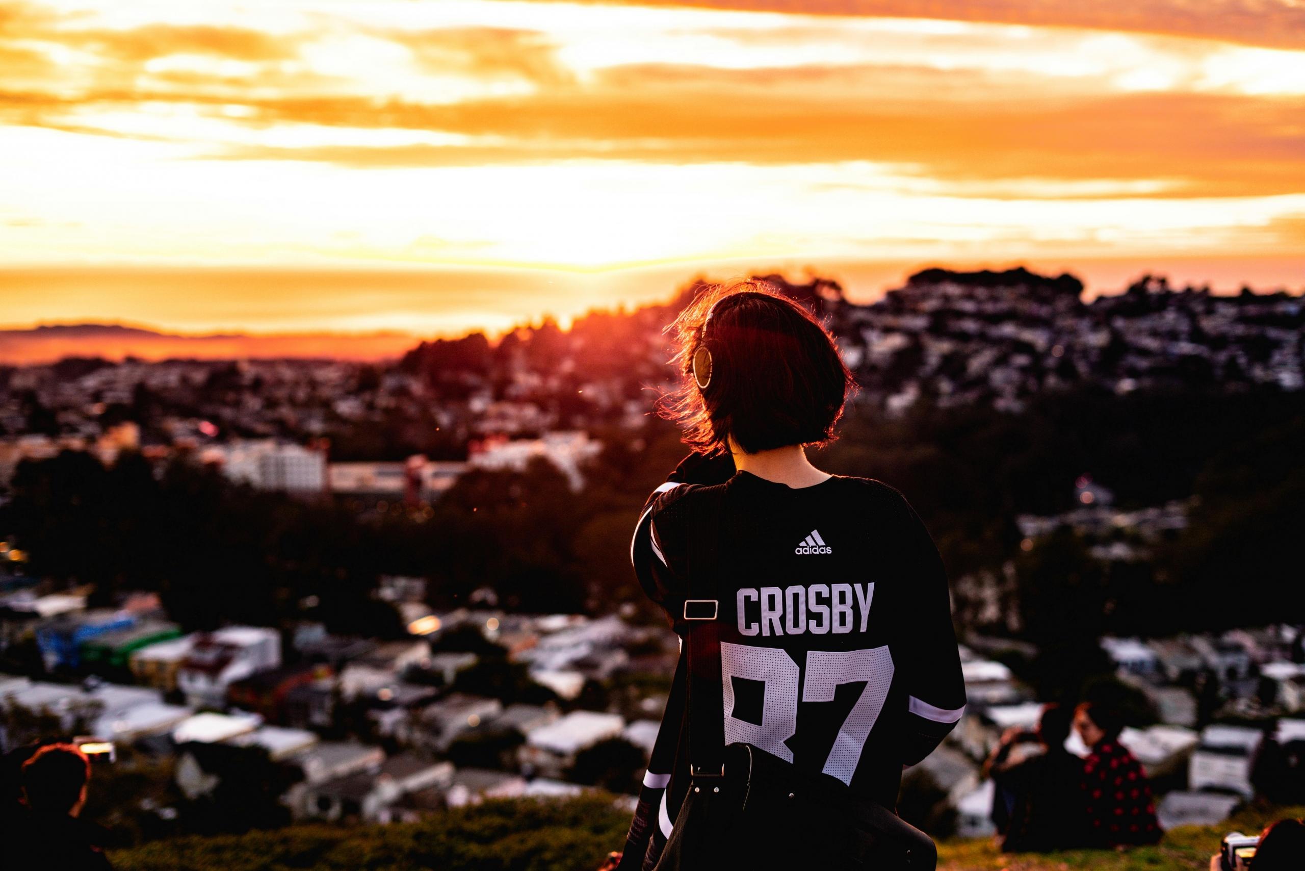 a hockey fan wears a Sidney Crosby jersey as they look out onto a sunset.