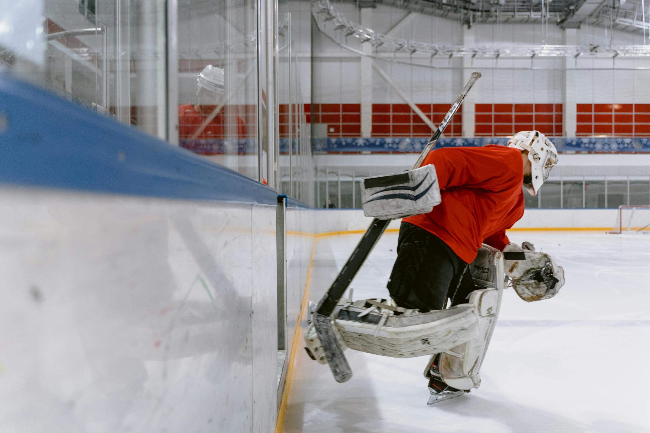 a hockey player enters the ice rink. He wears a red uniform.
