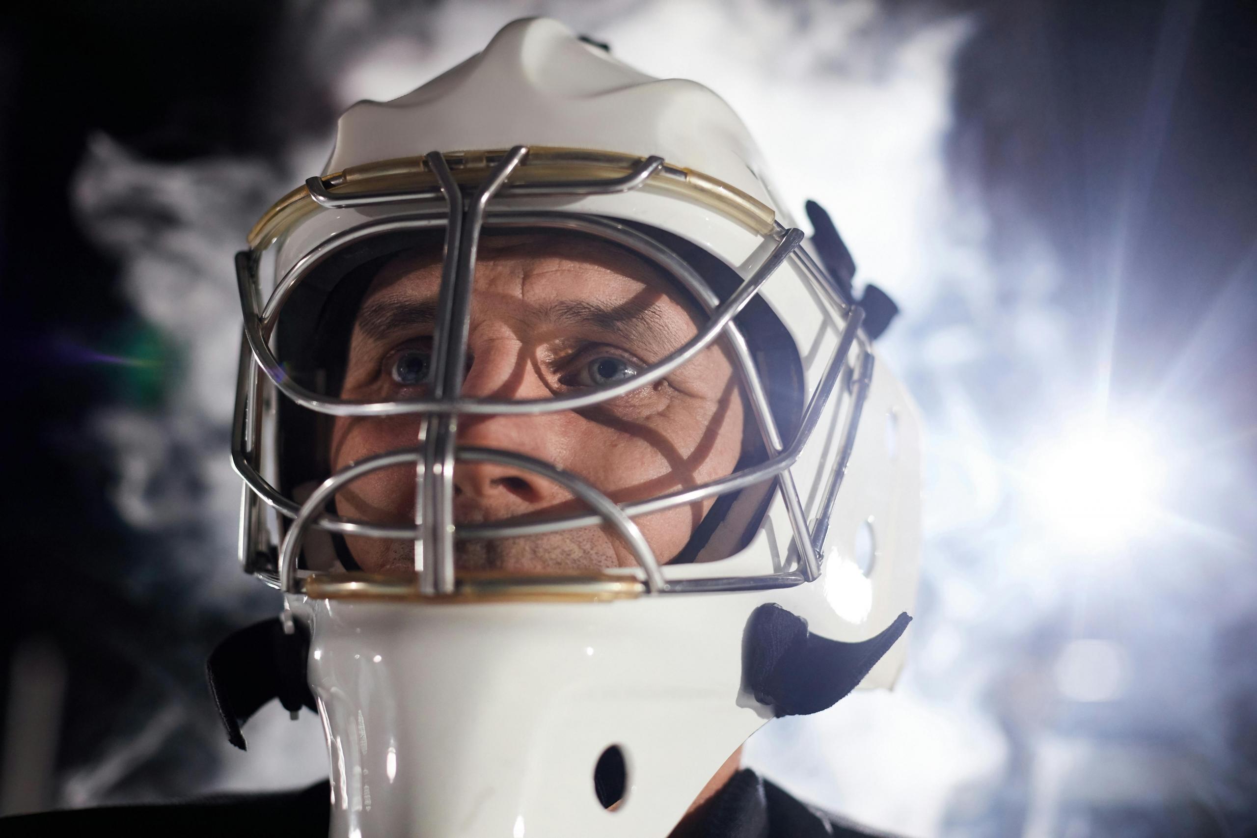 A close up of a hockey player's face. He wears a helmet.